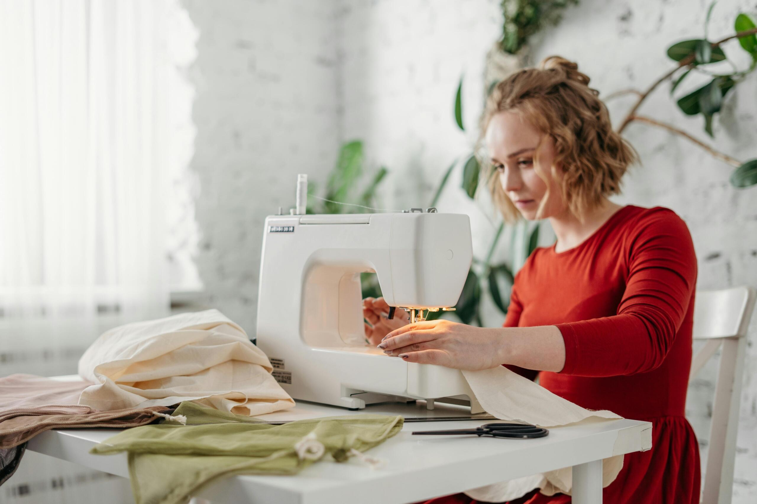 woman sitting at a table sewing fabric with a sewing machine
