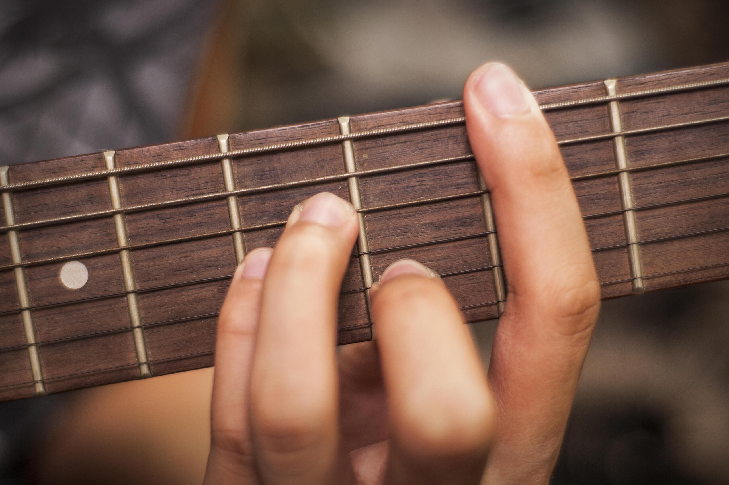 A hand plays a chord shape on the acoustic guitar.
