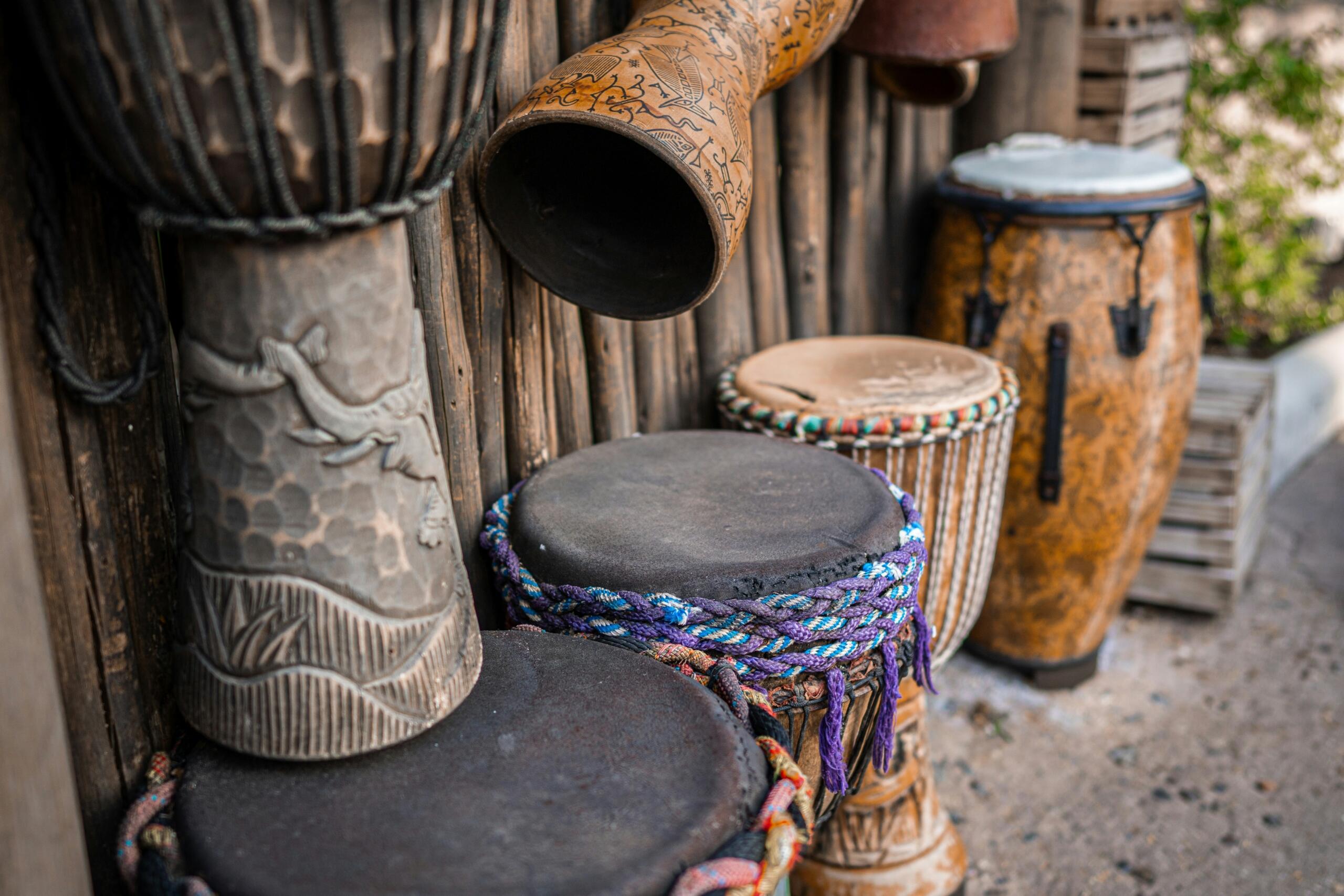 an assortment of traditional drums arranged neatly outside a structure