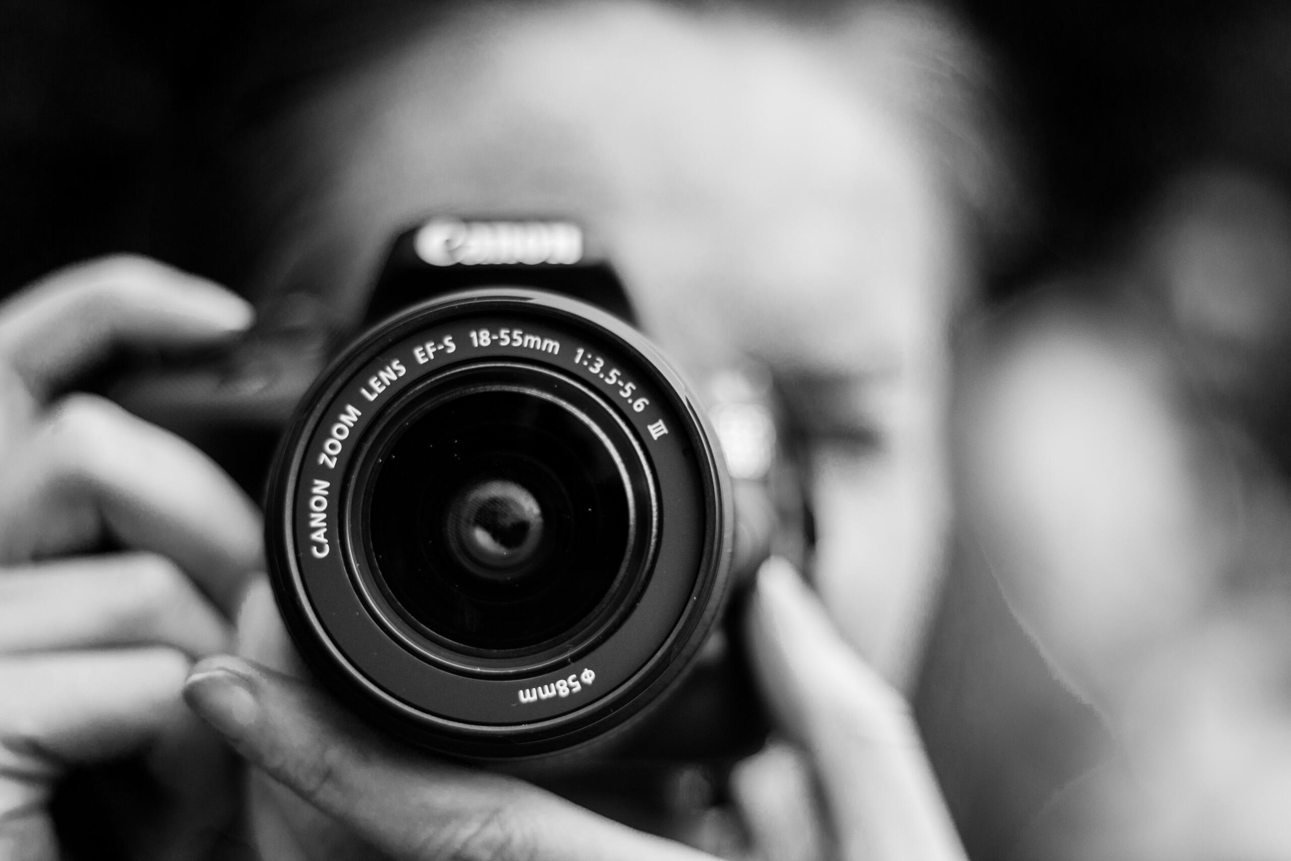 A black and white image of a woman holding a camera.