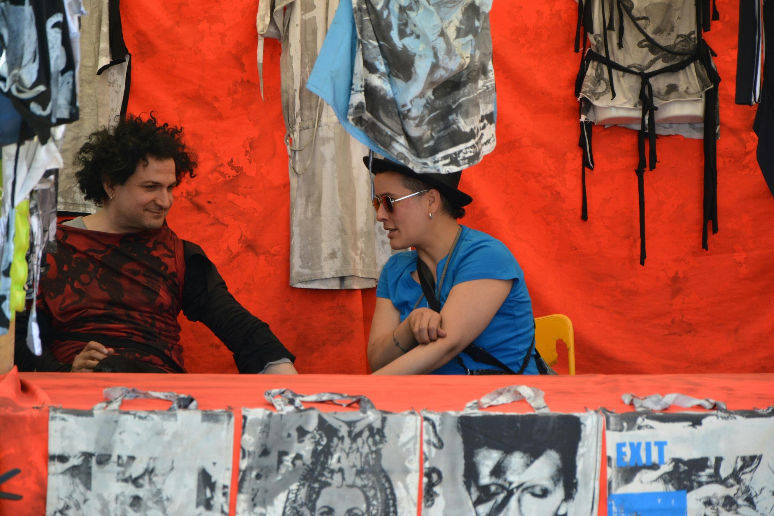 Two people look after a stand at a market.
