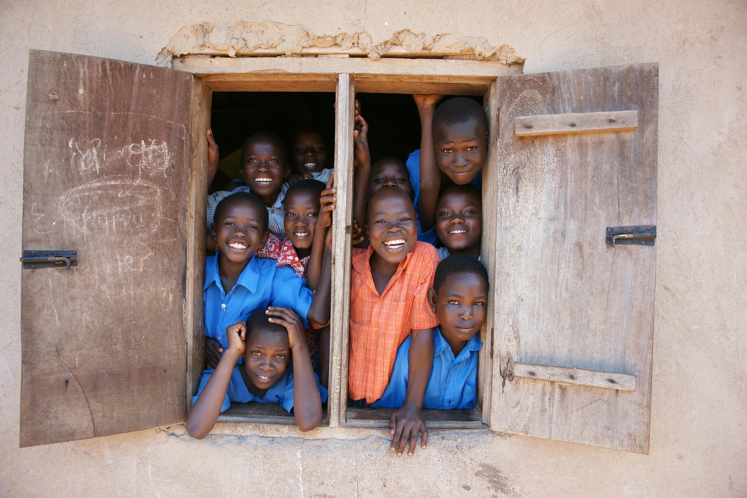 A group of children at the window of a rural classroom. 