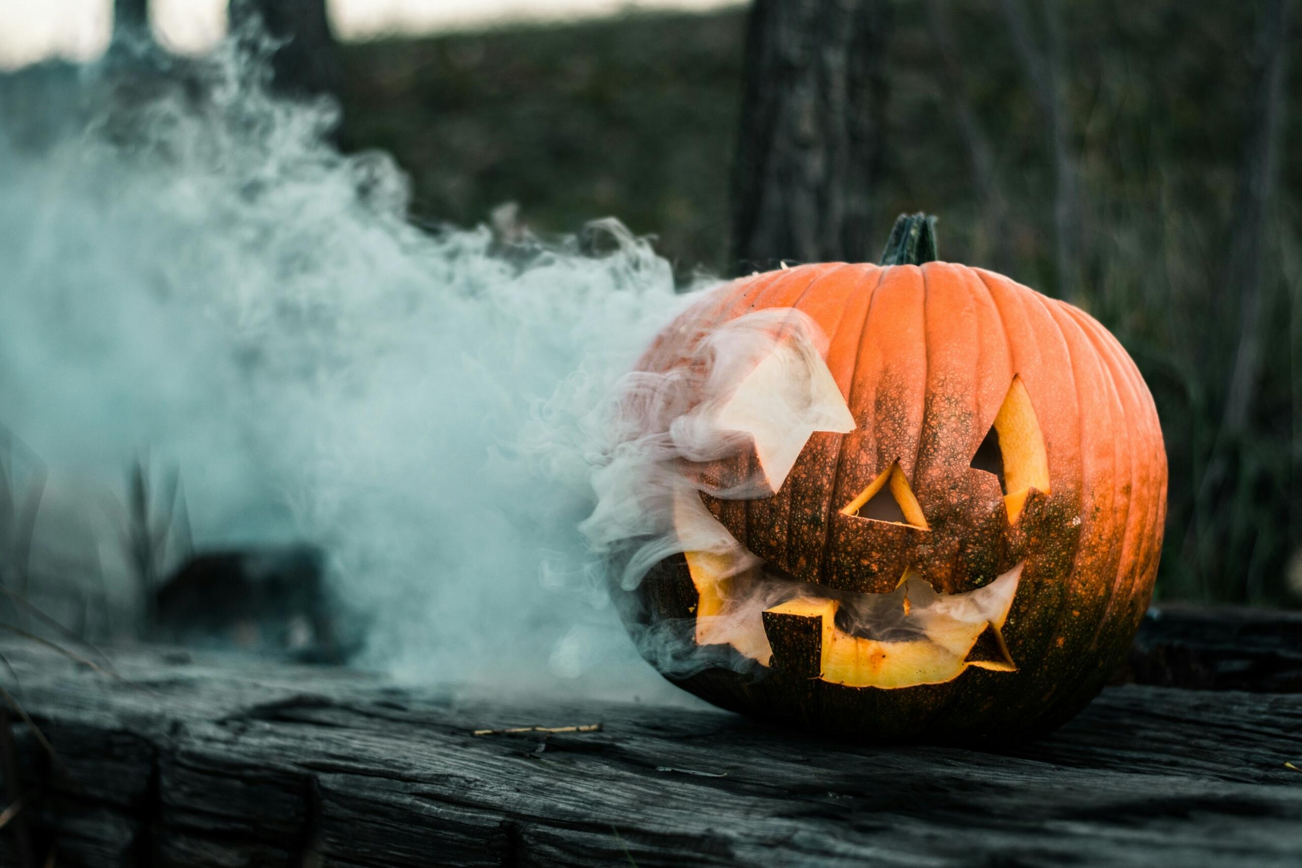 jack-o-lantern with smoke pouring out of it placed outside on a gloomy day