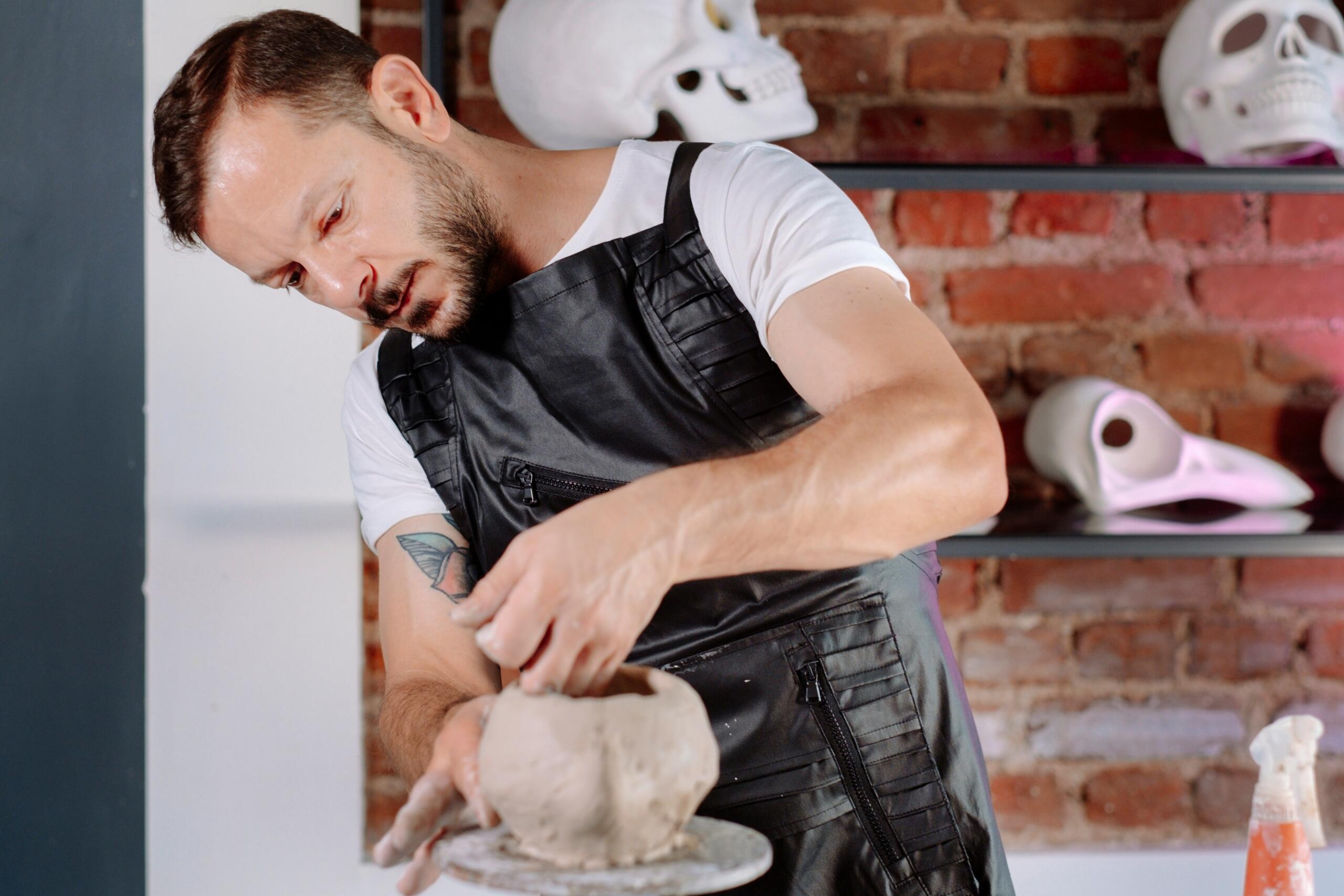 A ceramic artist works the edges of a pot in a studio.