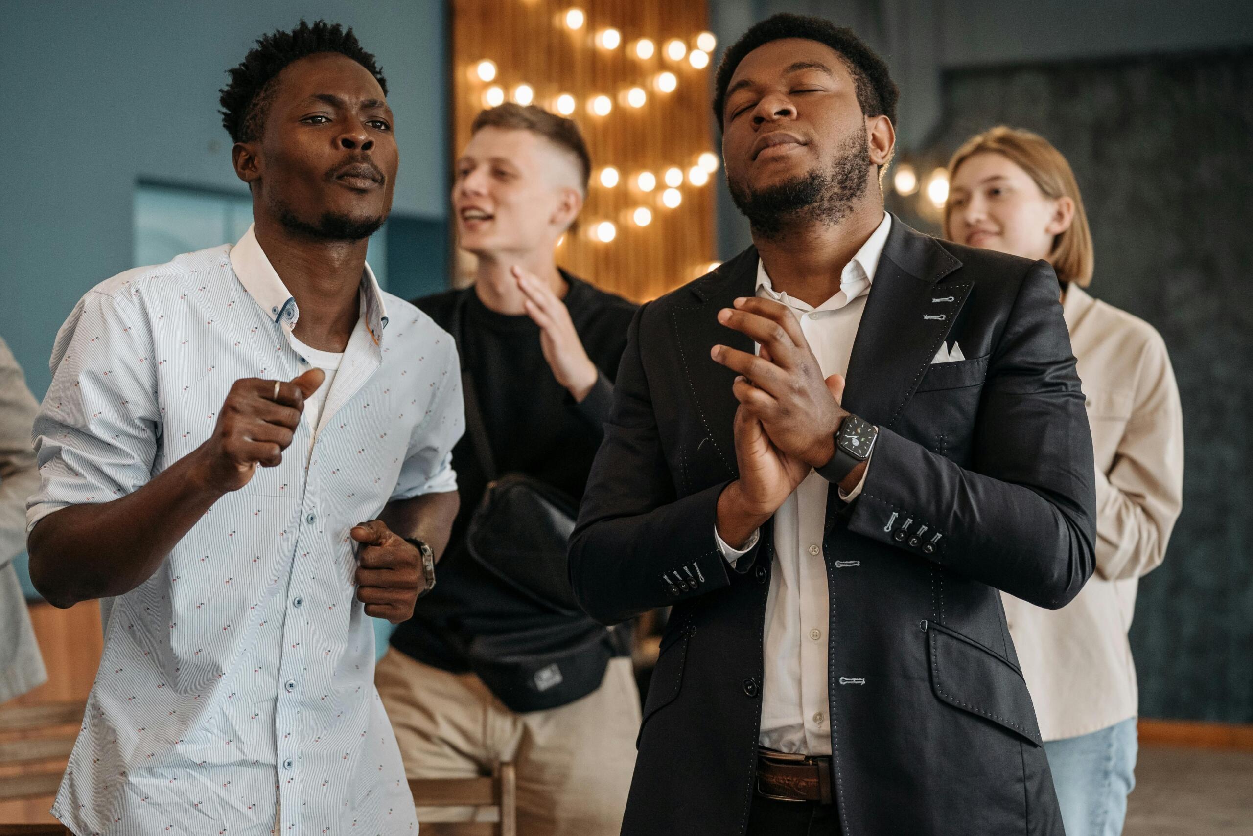 people standing and singing while clapping their hands