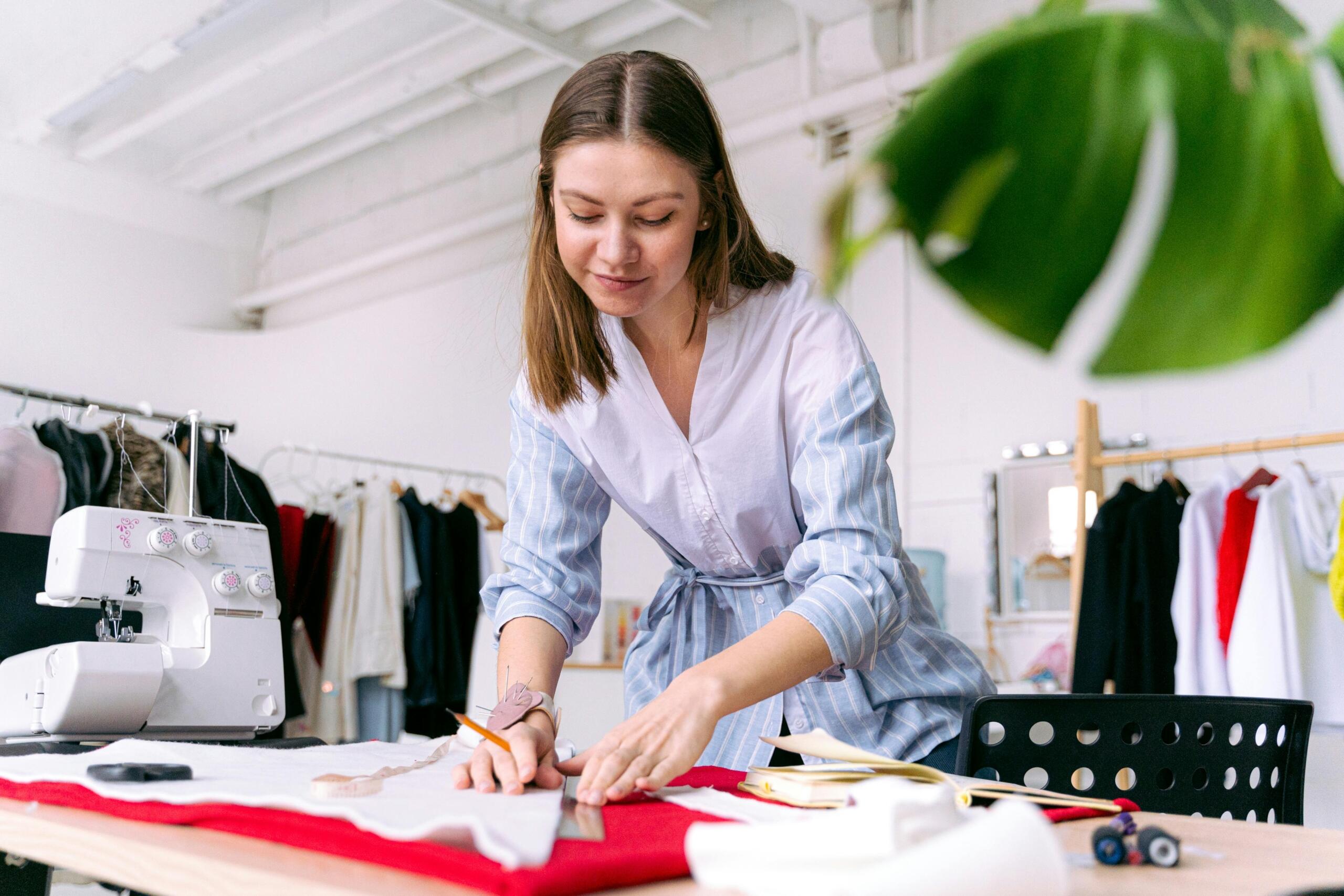 woman-in-blue-dress-using-a-ruler- to-measure-and-cut-fabric