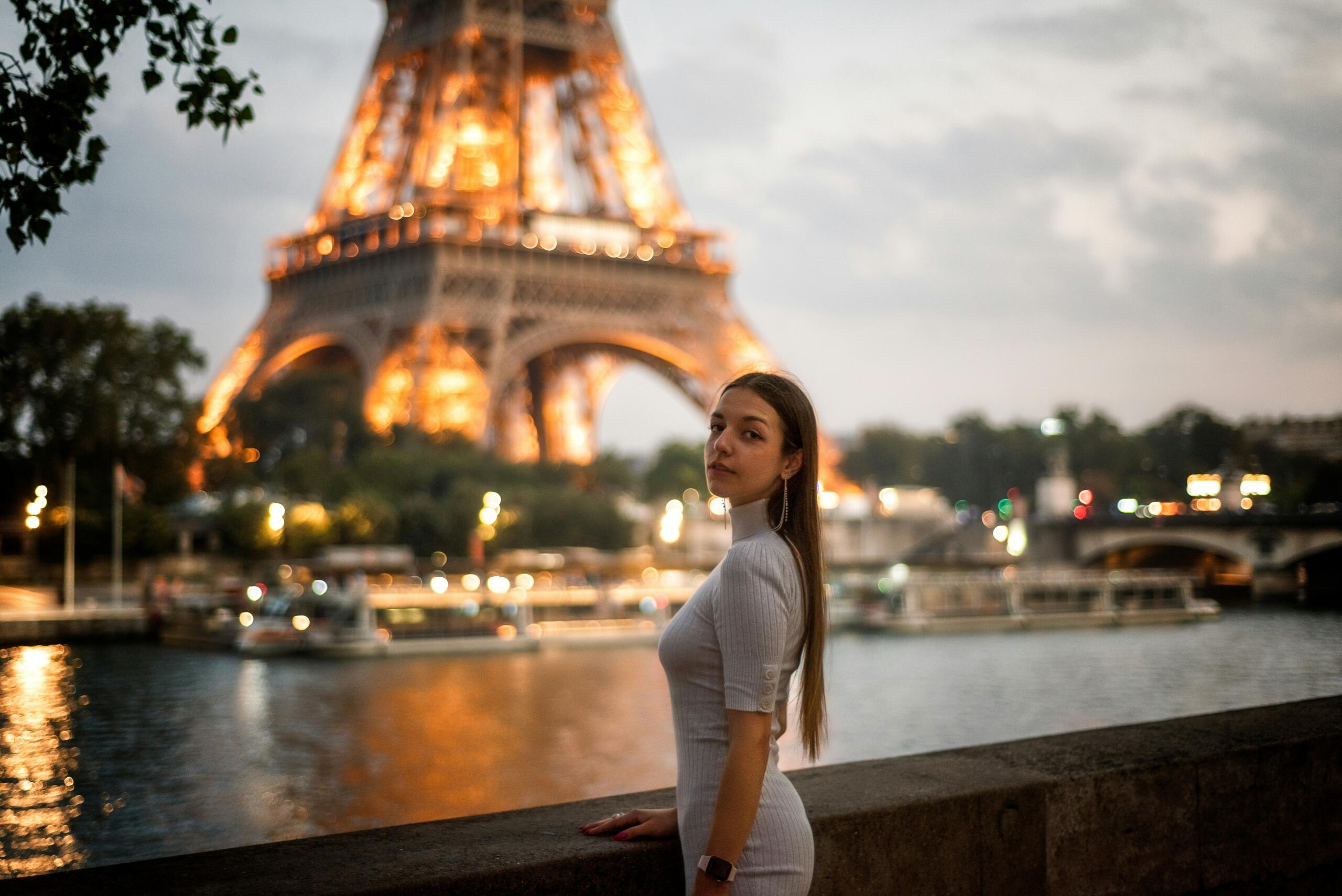 A young woman enjoys dusk with a view of the Eiffel Tower.
