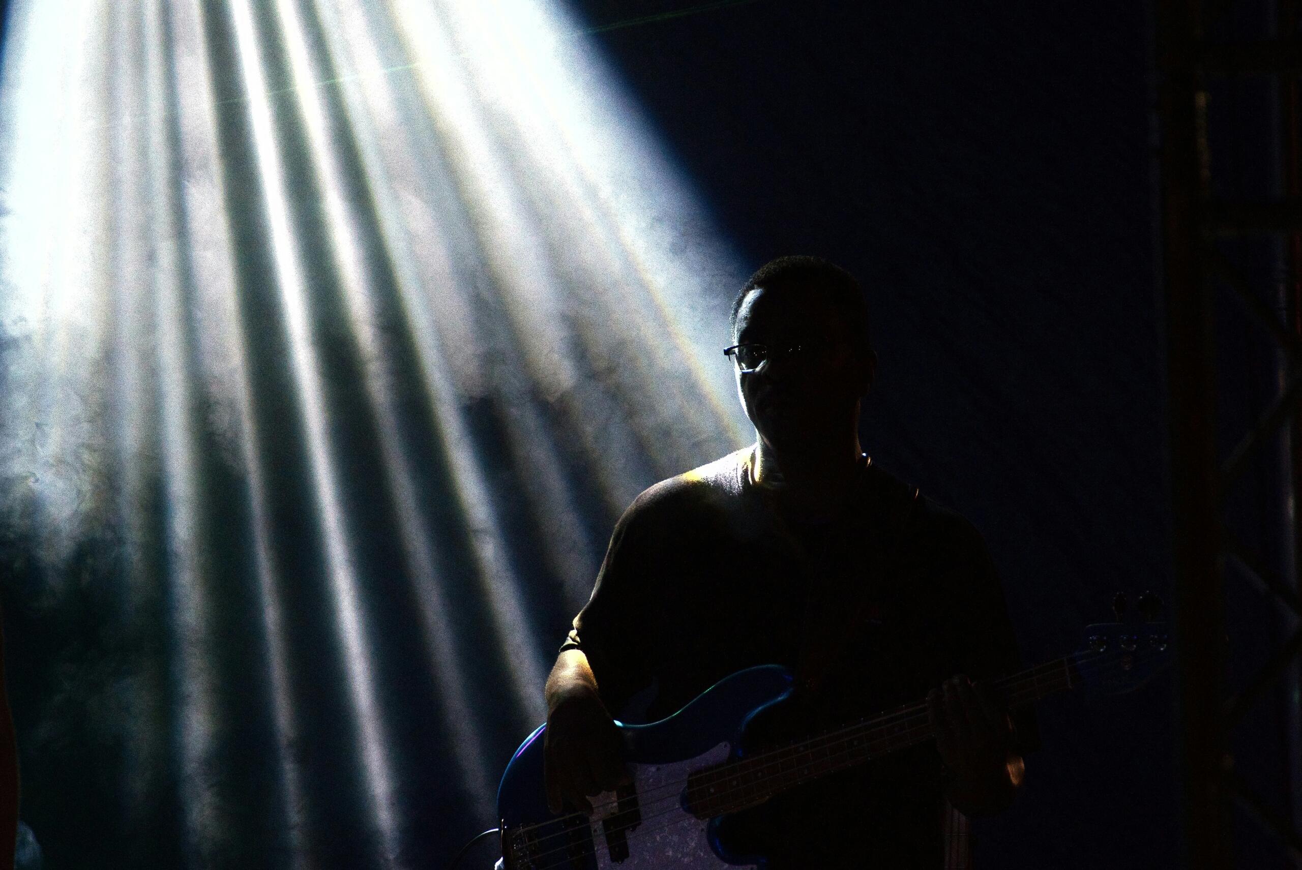 A spotlight puts a guitar  player in silhouette.