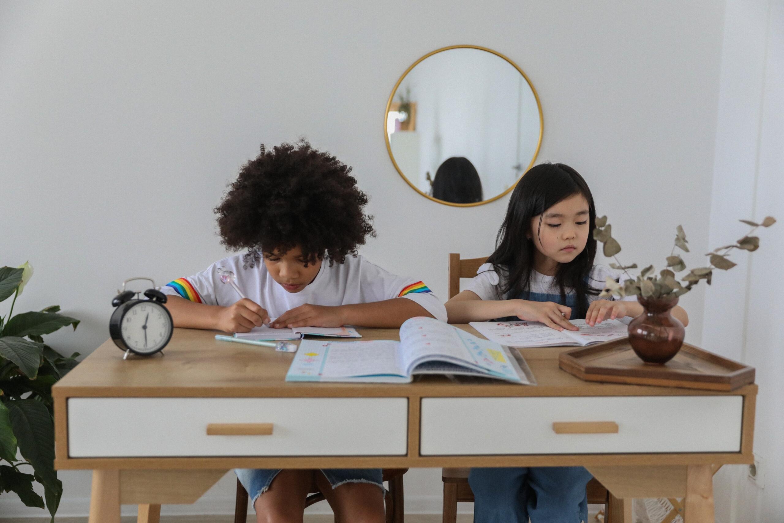 a boy and a girl sitting at the same desk writing in exercise books