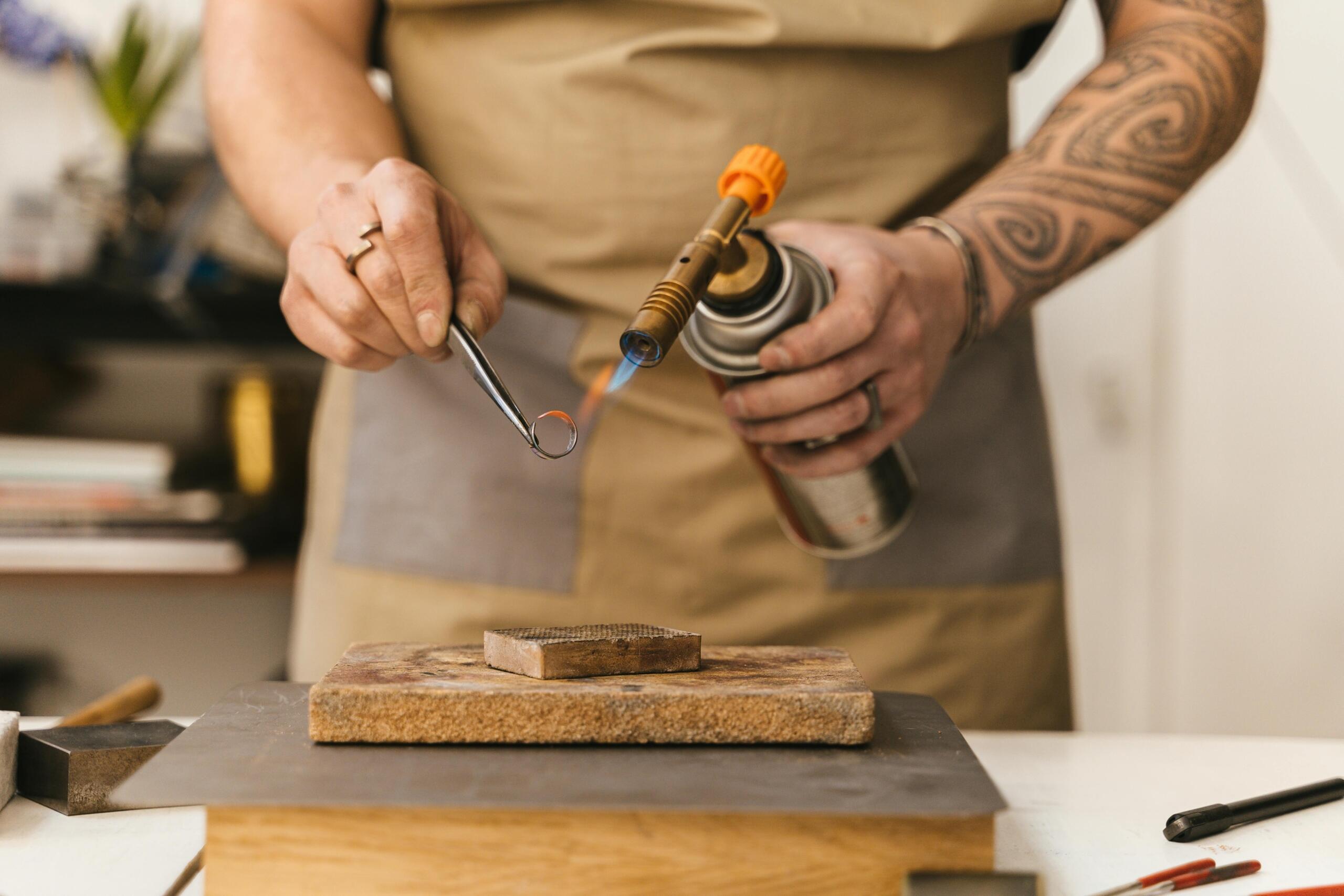 man using a blowtorch to forge a ring