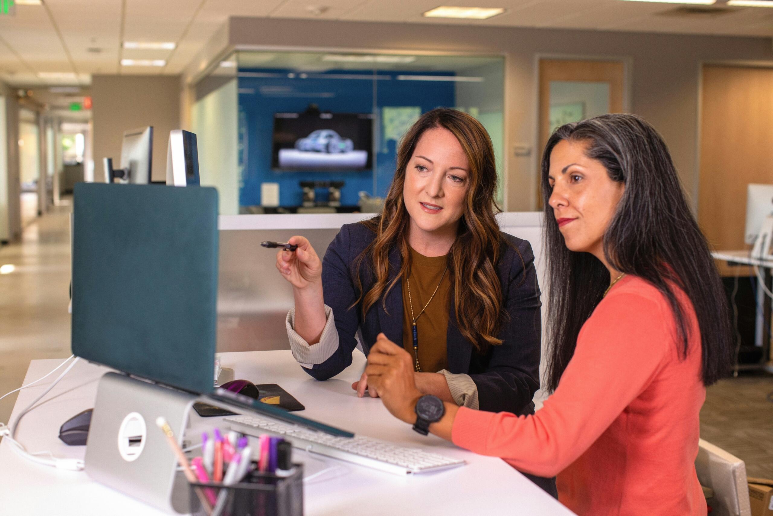 two women in an office looking at the display on a laptop screen