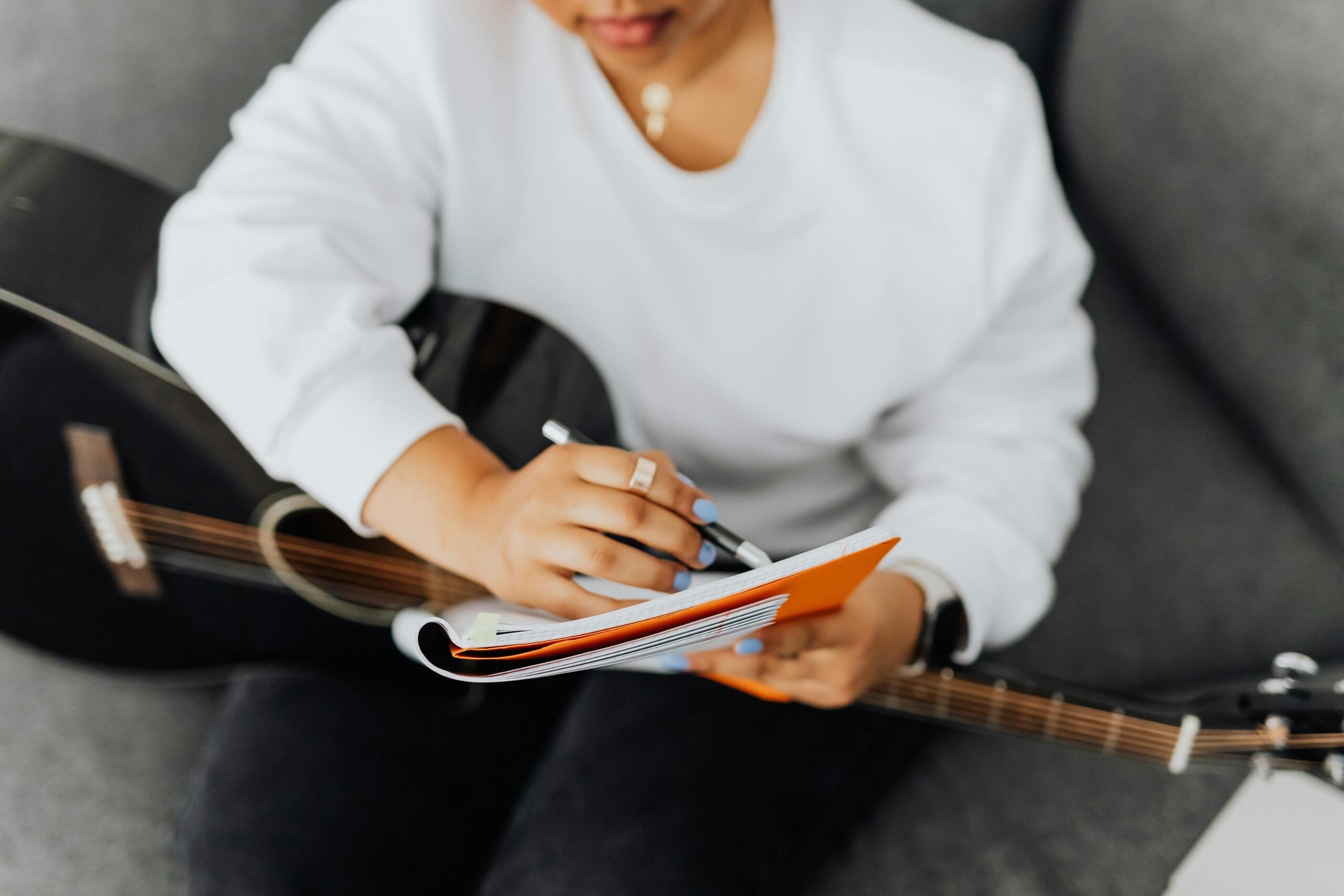 A guitar student with notes and her instrument.