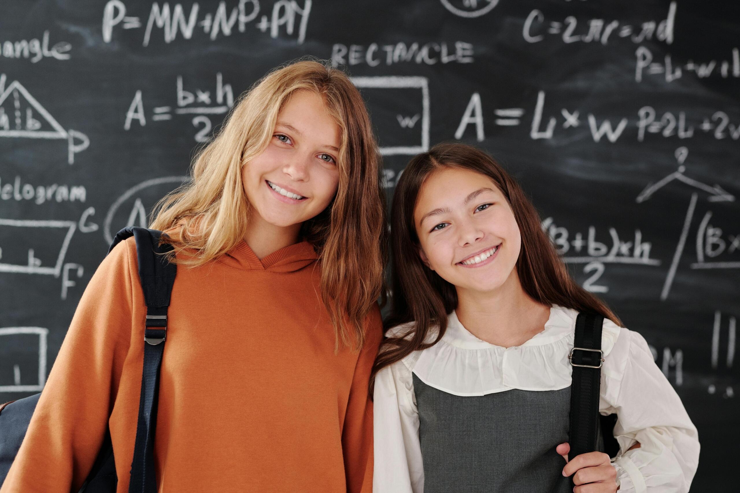 Two senior learners in front of a maths blackboard. 