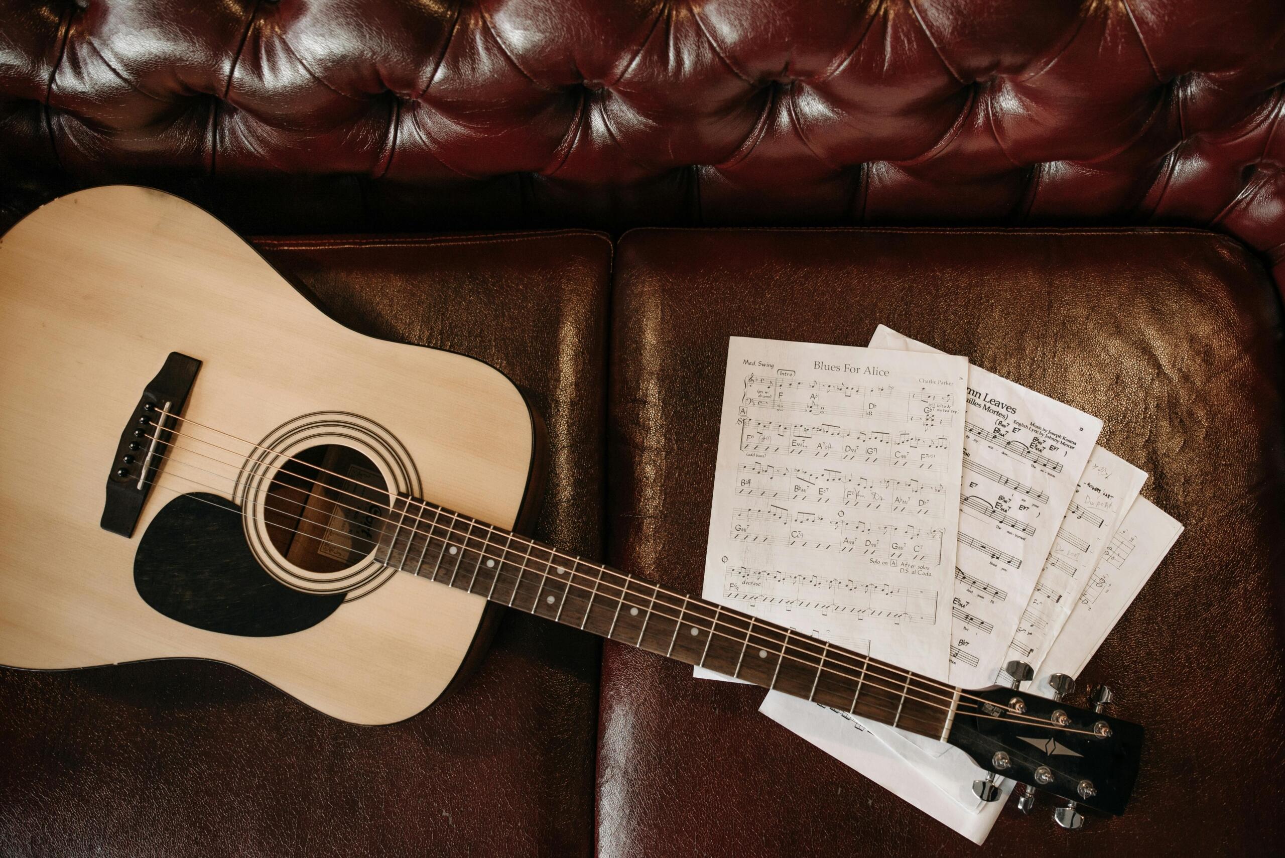 A guitar with sheet music beside it.