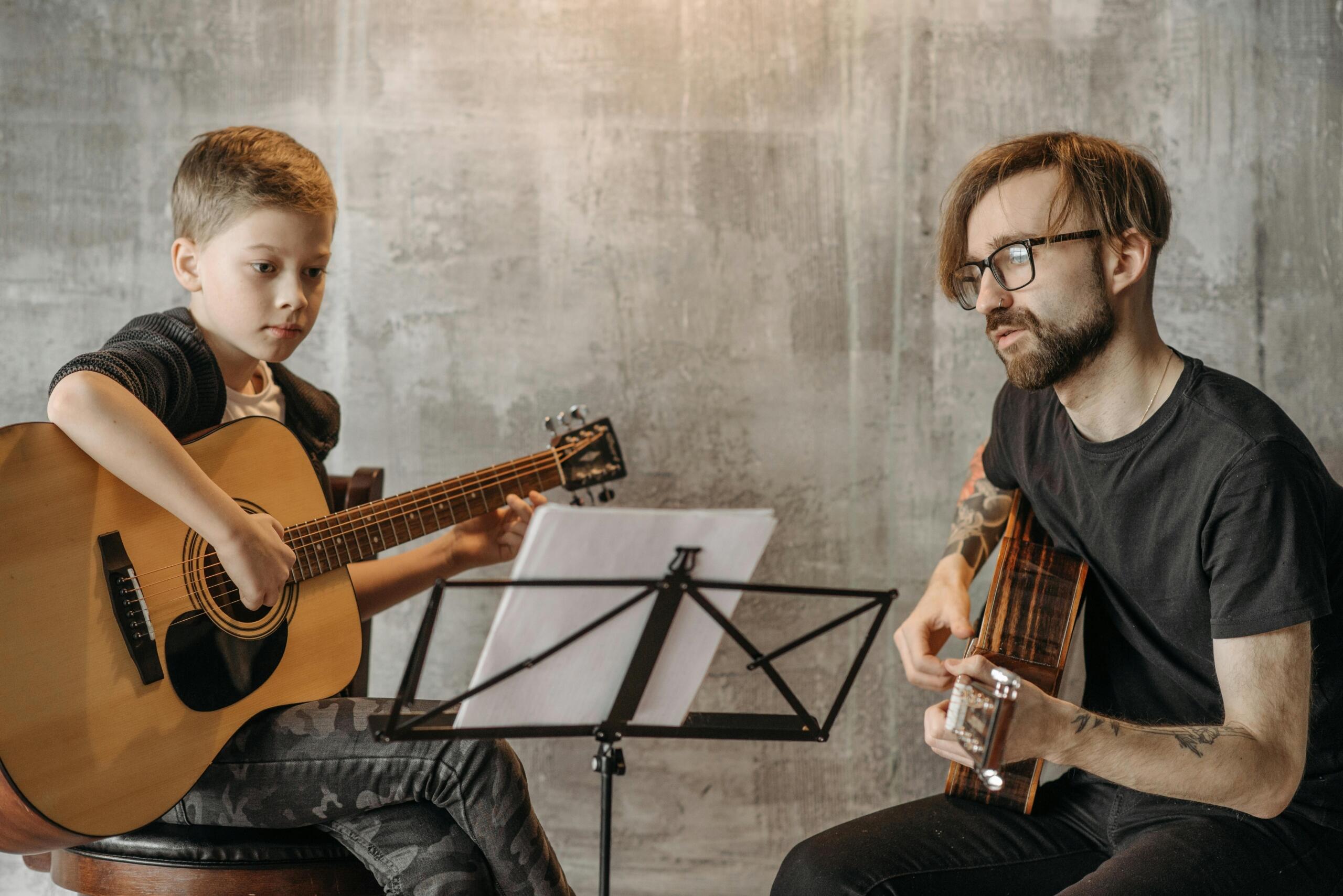 A guitar tutor and student practice together.