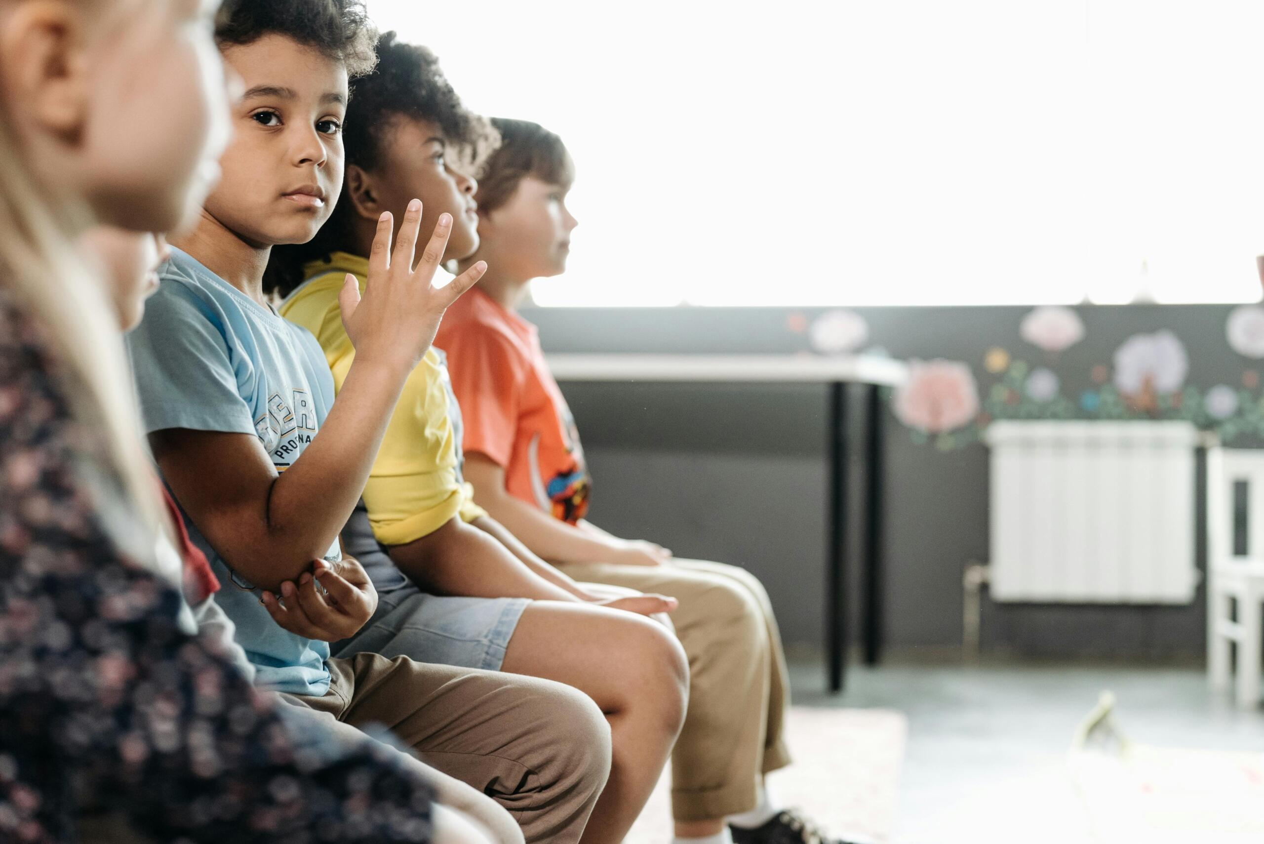 young children sitting in chairs placed side-by-side in a row