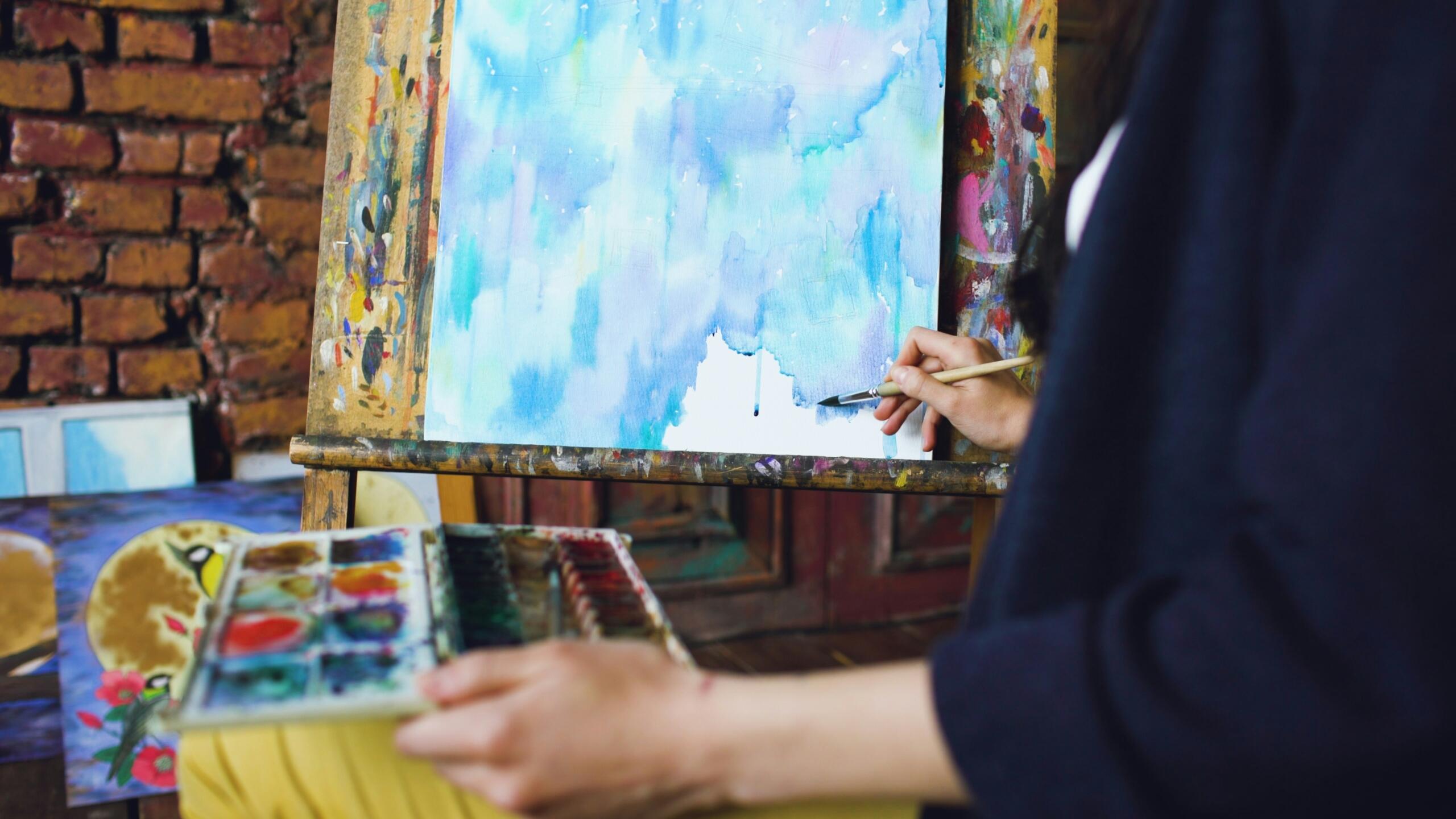 painter painting on canvas in shades of blue and purple