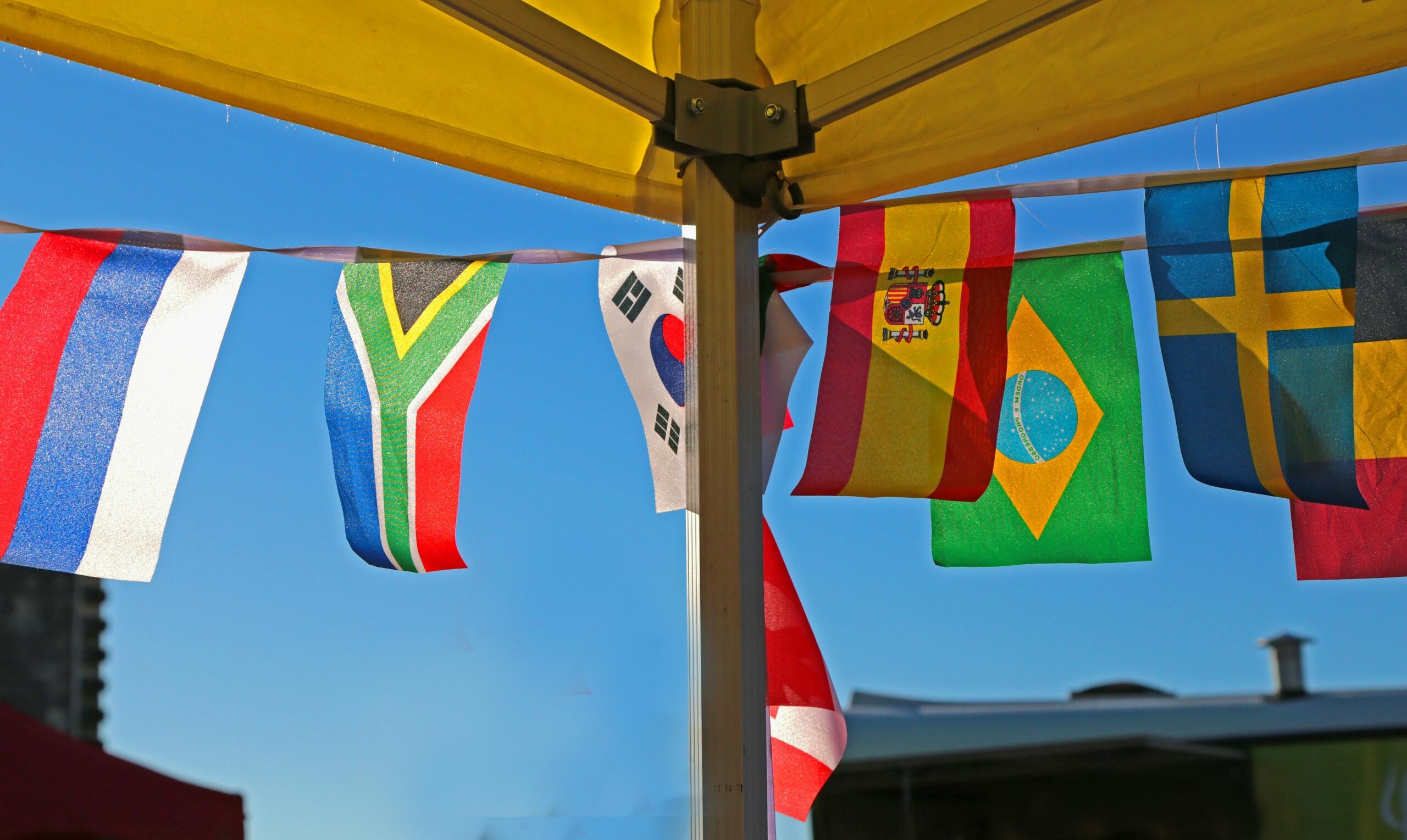 A collection of brightly colored national flags is strung around a yellow gazebo to attract attention.