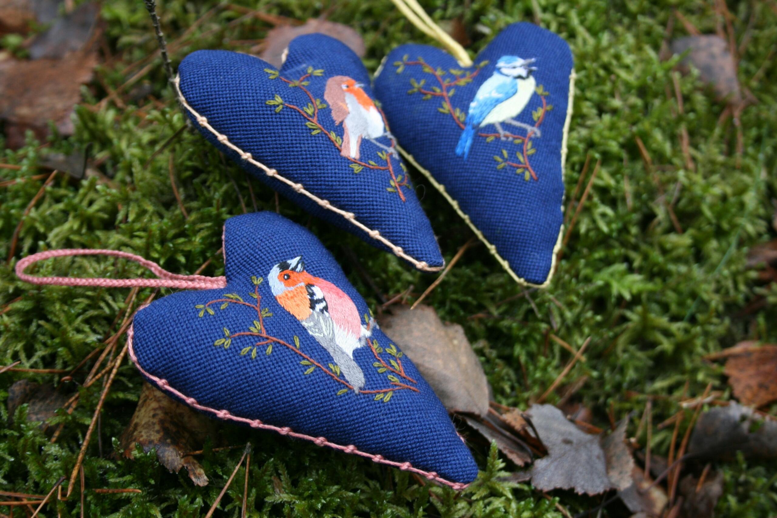 hand-sewn heart-shaped ornaments with birds embroidered on the front