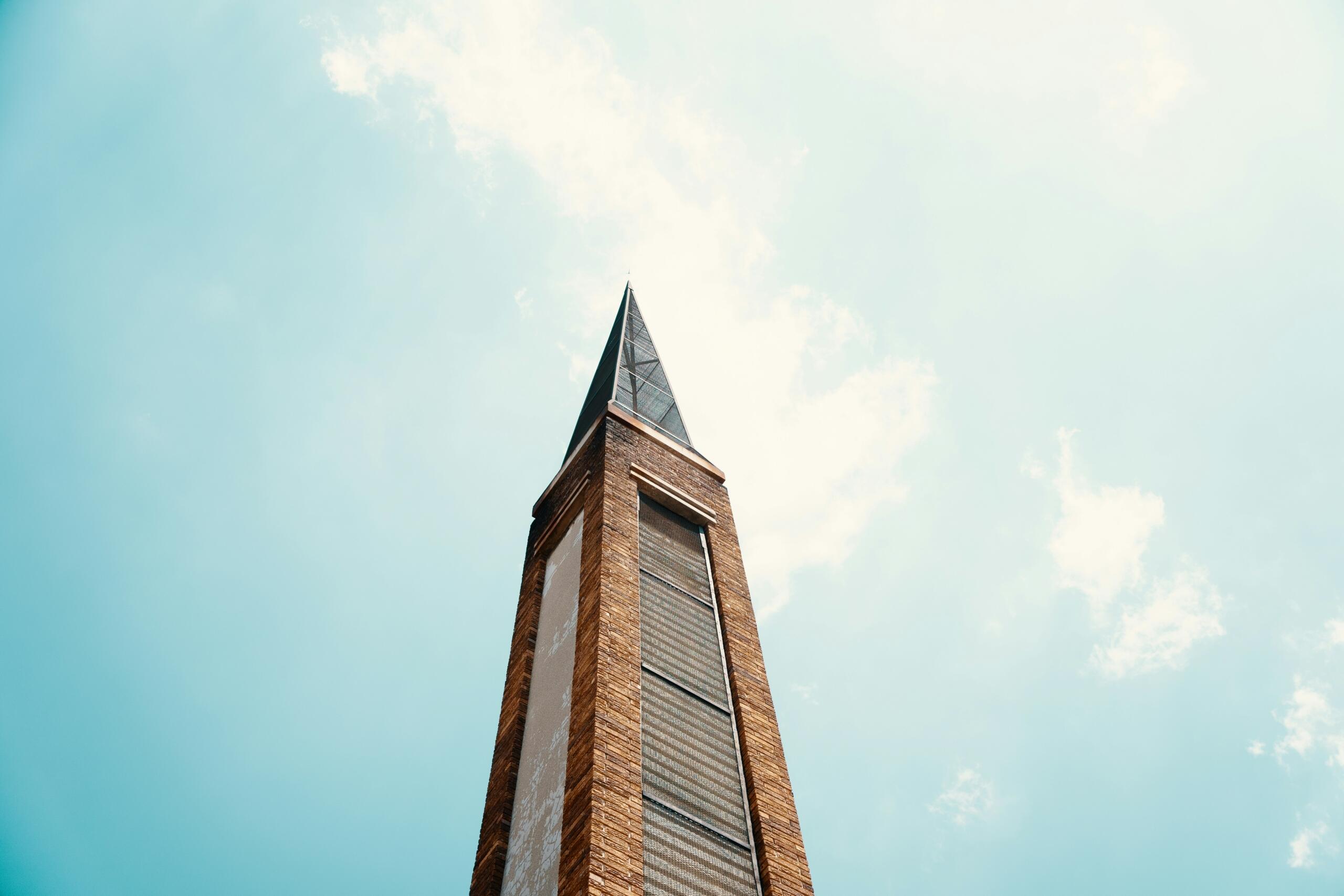 A church steeple stands proudly against a blue sky.