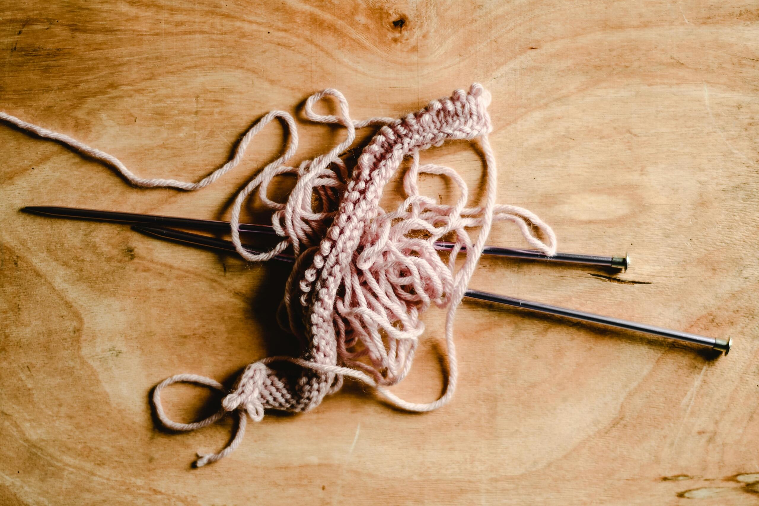 knitting project with needles and wool placed on wooden surface