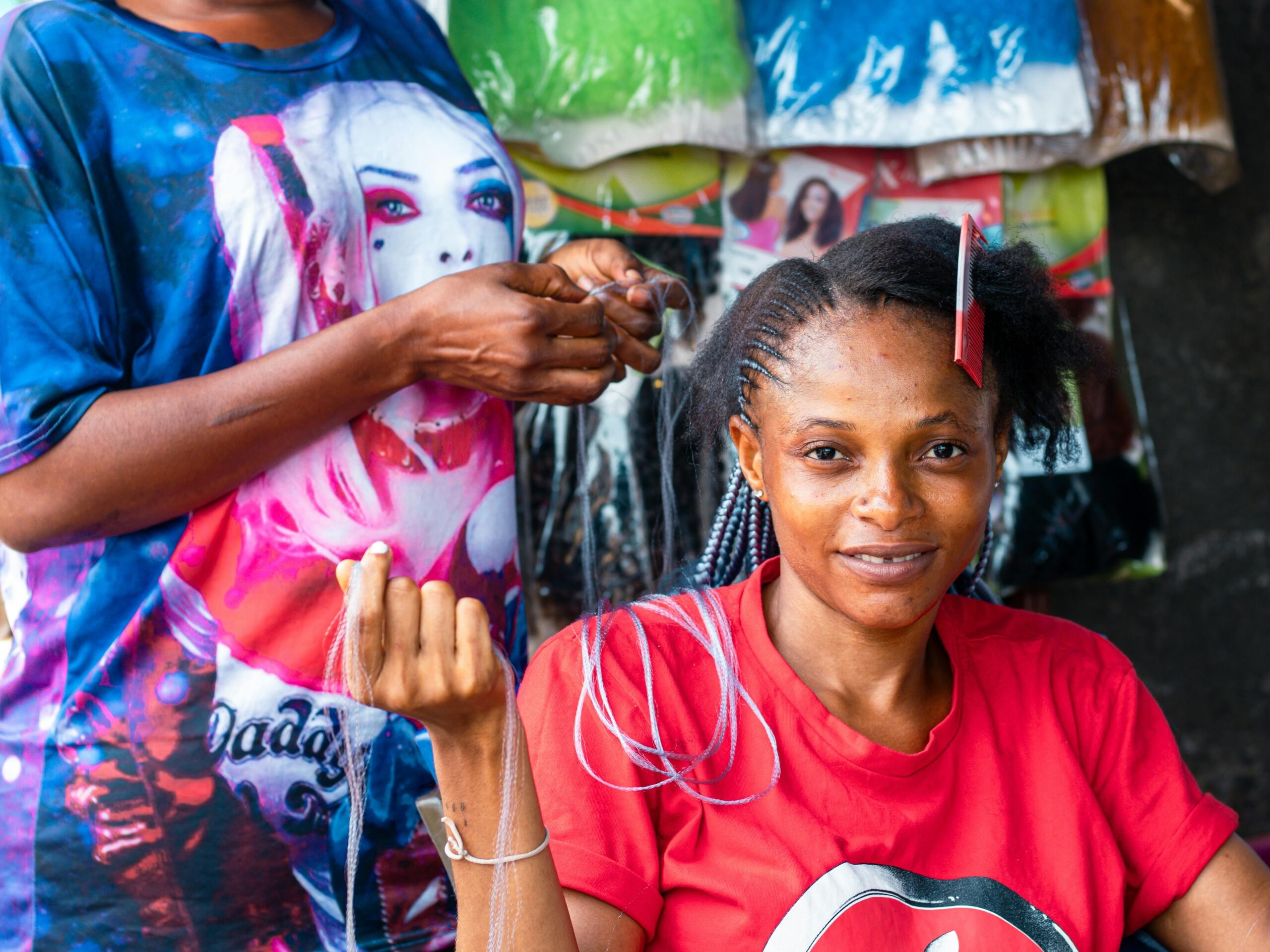 A hairdresser looks after a client's braids. 
