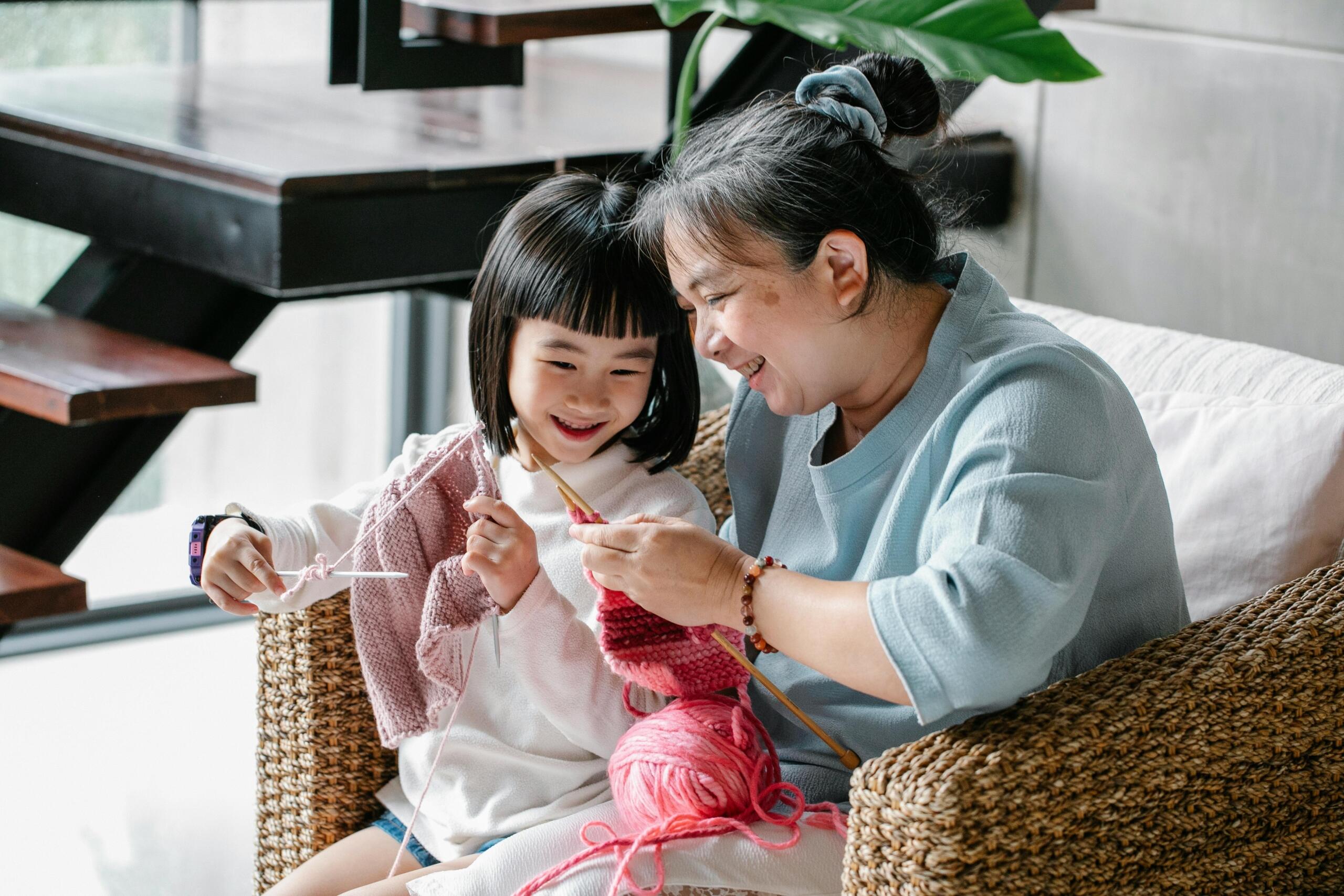 woman teaching young child to knit sitting in the same chair
