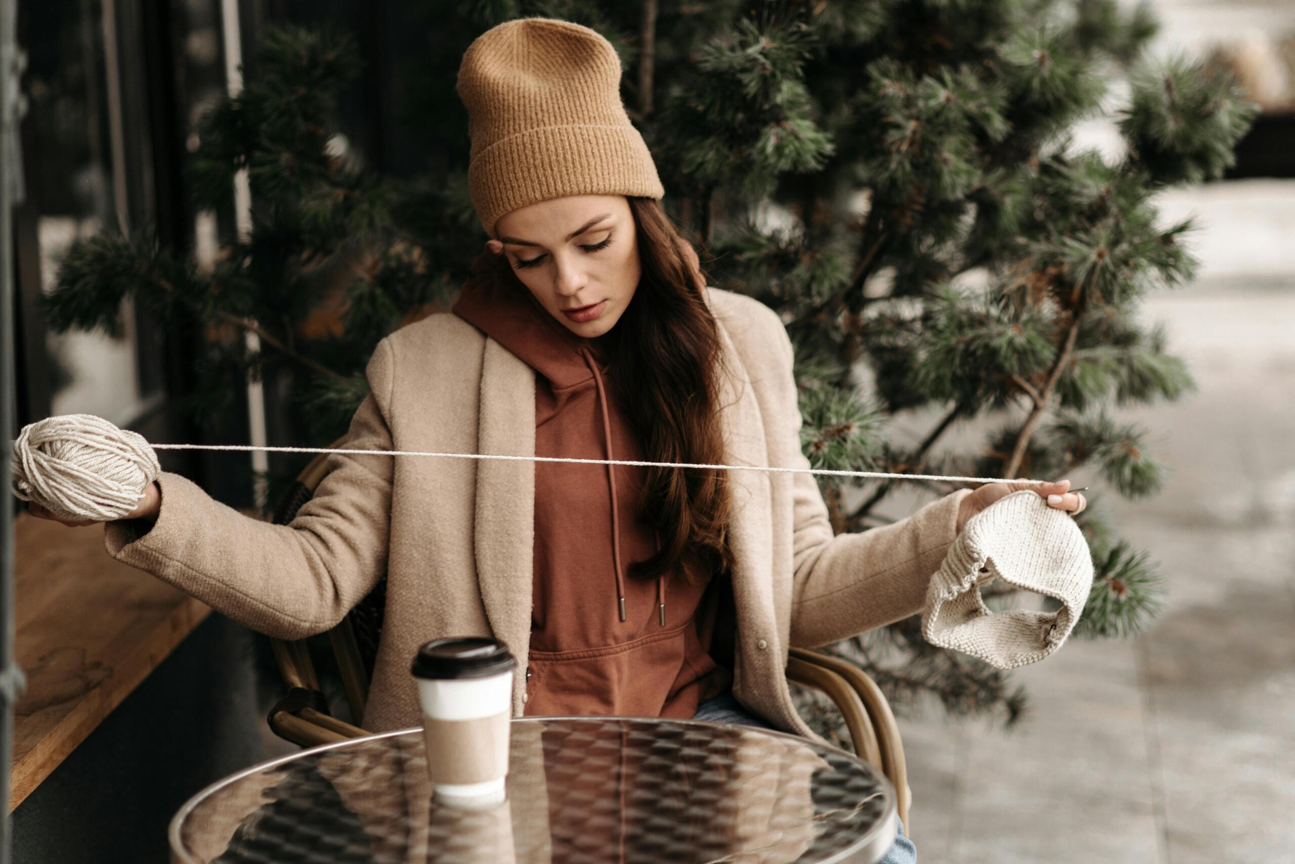 woman sitting at outdoor cafe table knitting