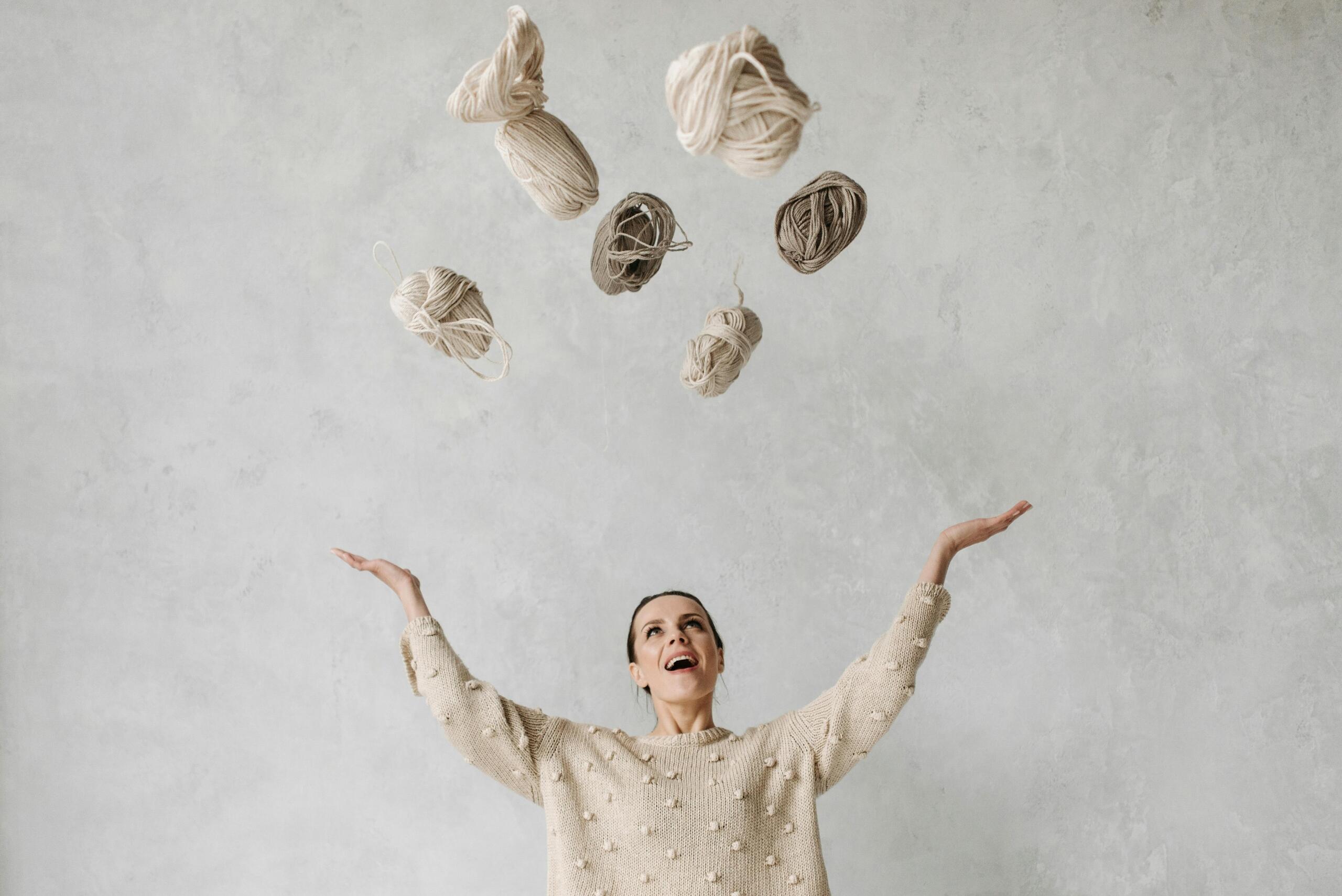 woman throwing skeins of wool up in the air