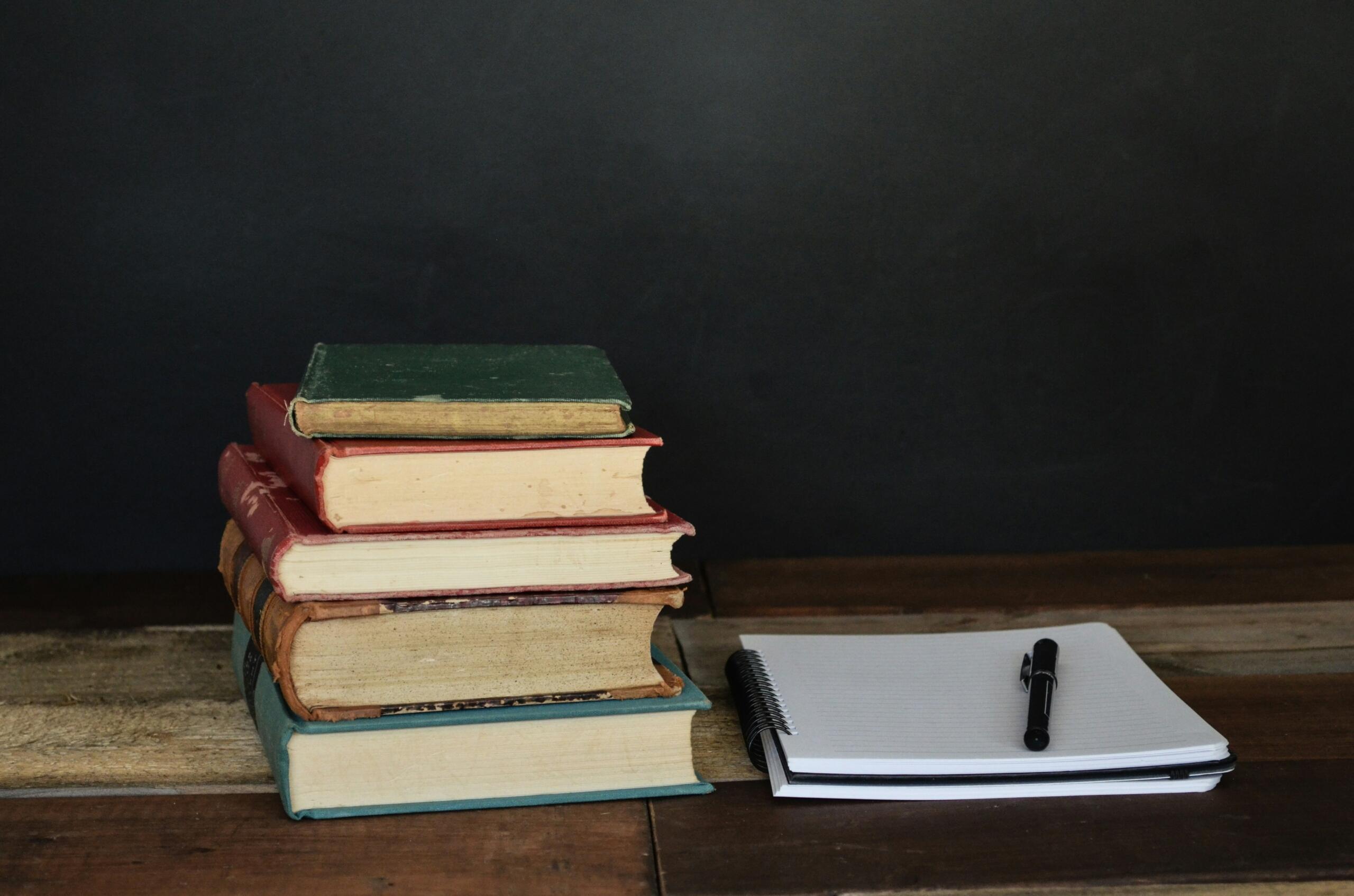 An image of a stack of books and a notepad. 