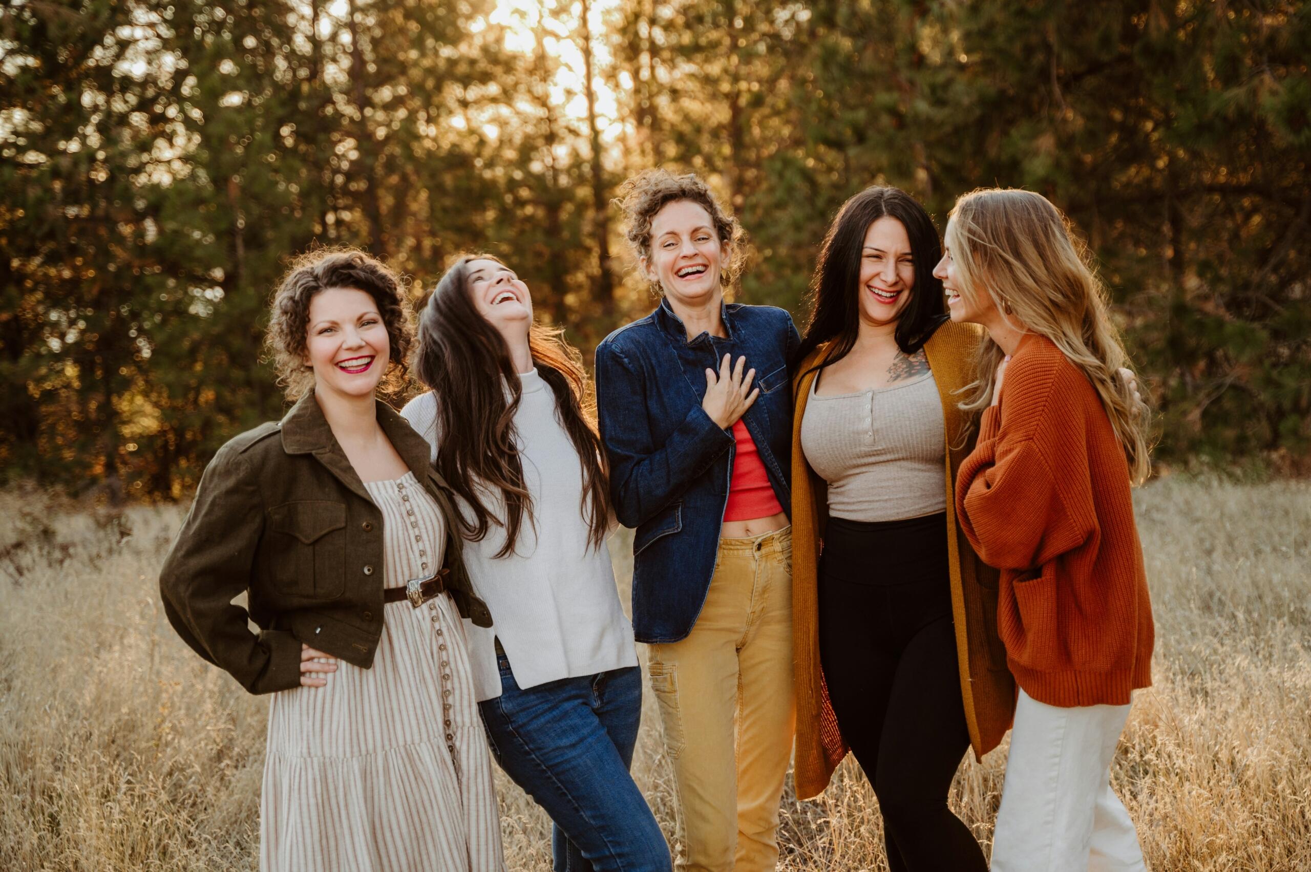 a group of laughing women in a forest at sunset