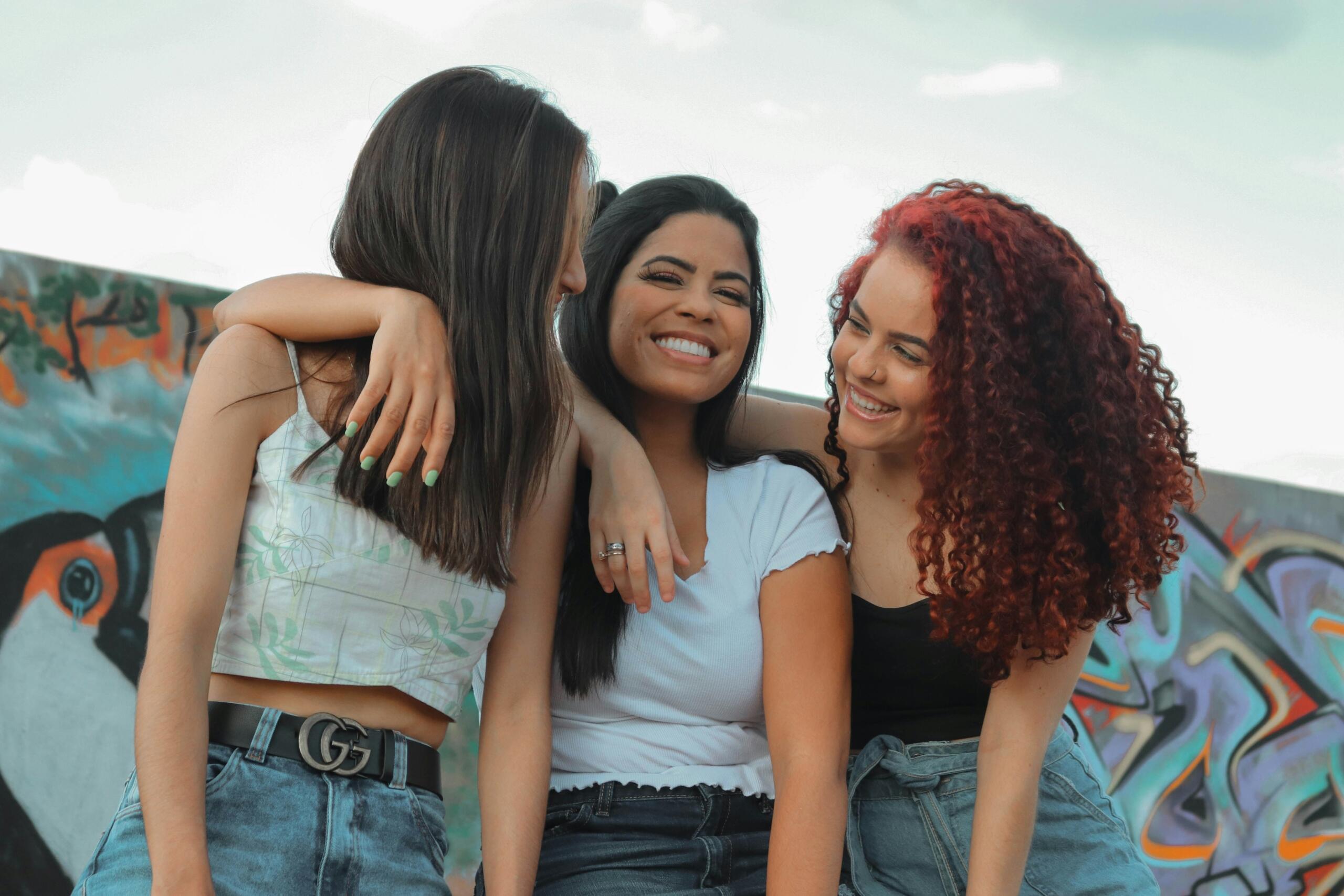 three young women smiling with theeir arms around each others' shoulders