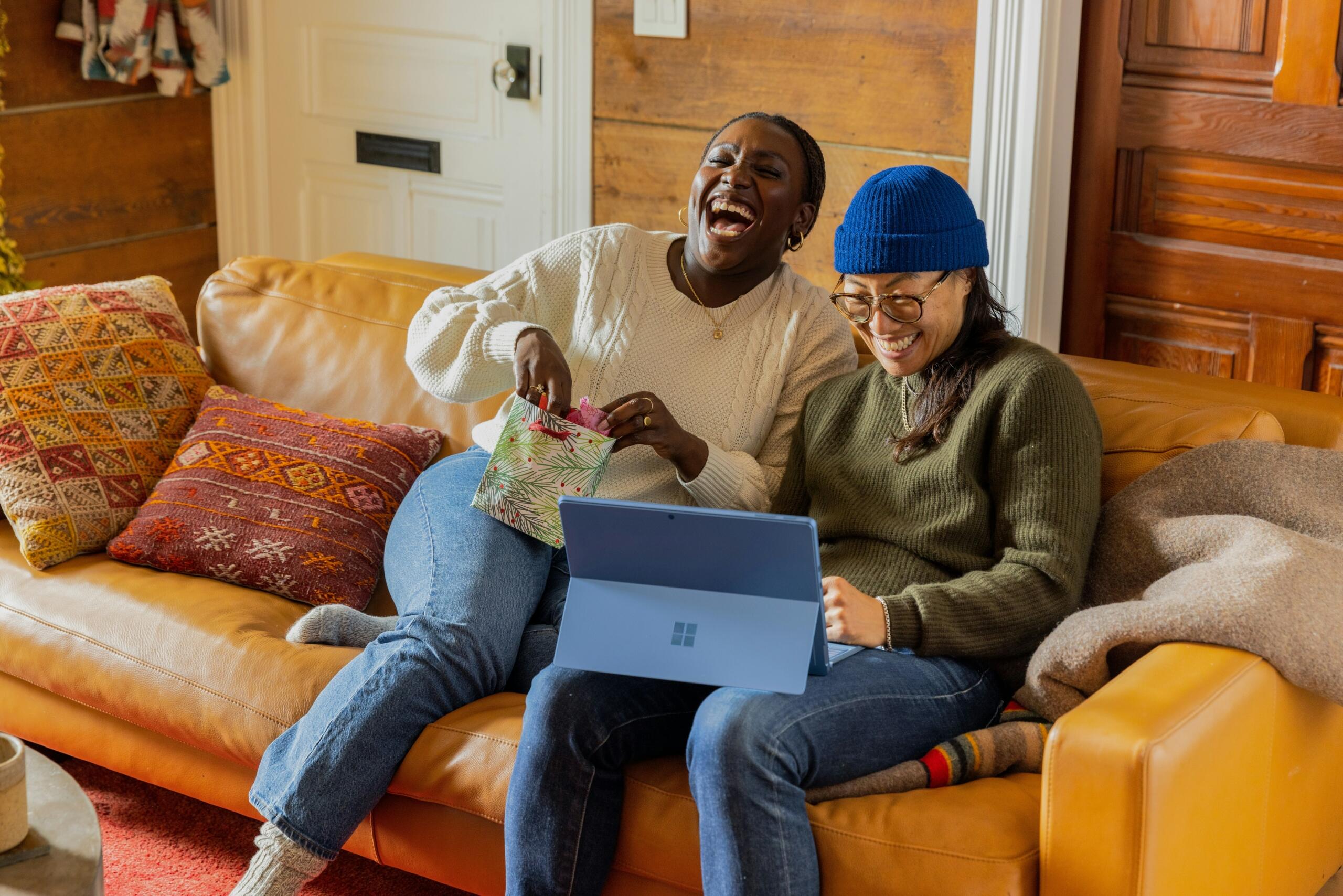 two women sitting on a sofa laughing