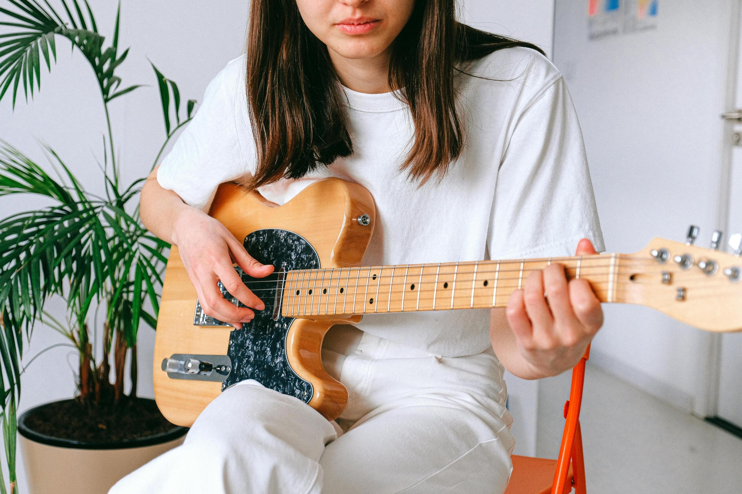 woman sitting on a red chair playing guitar