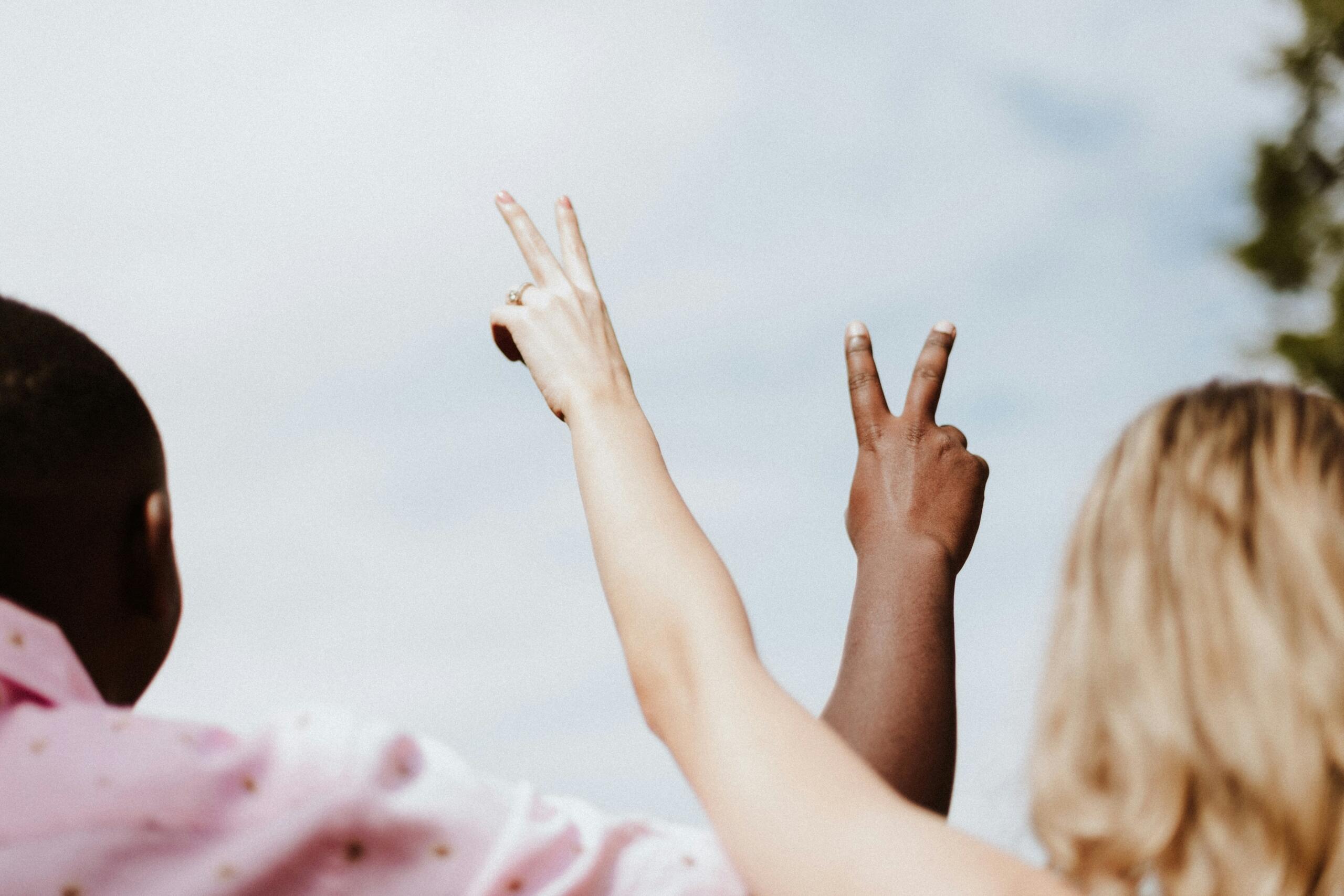two people outside holding their hands up in peace signs