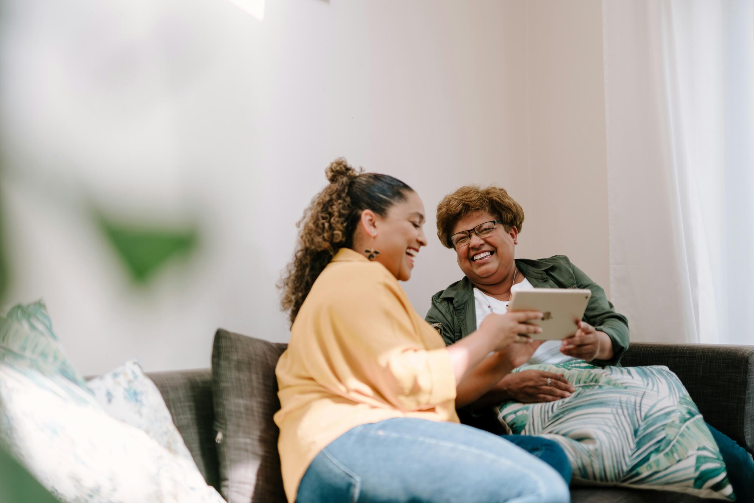 a young women showing an older woman how to use a tablet