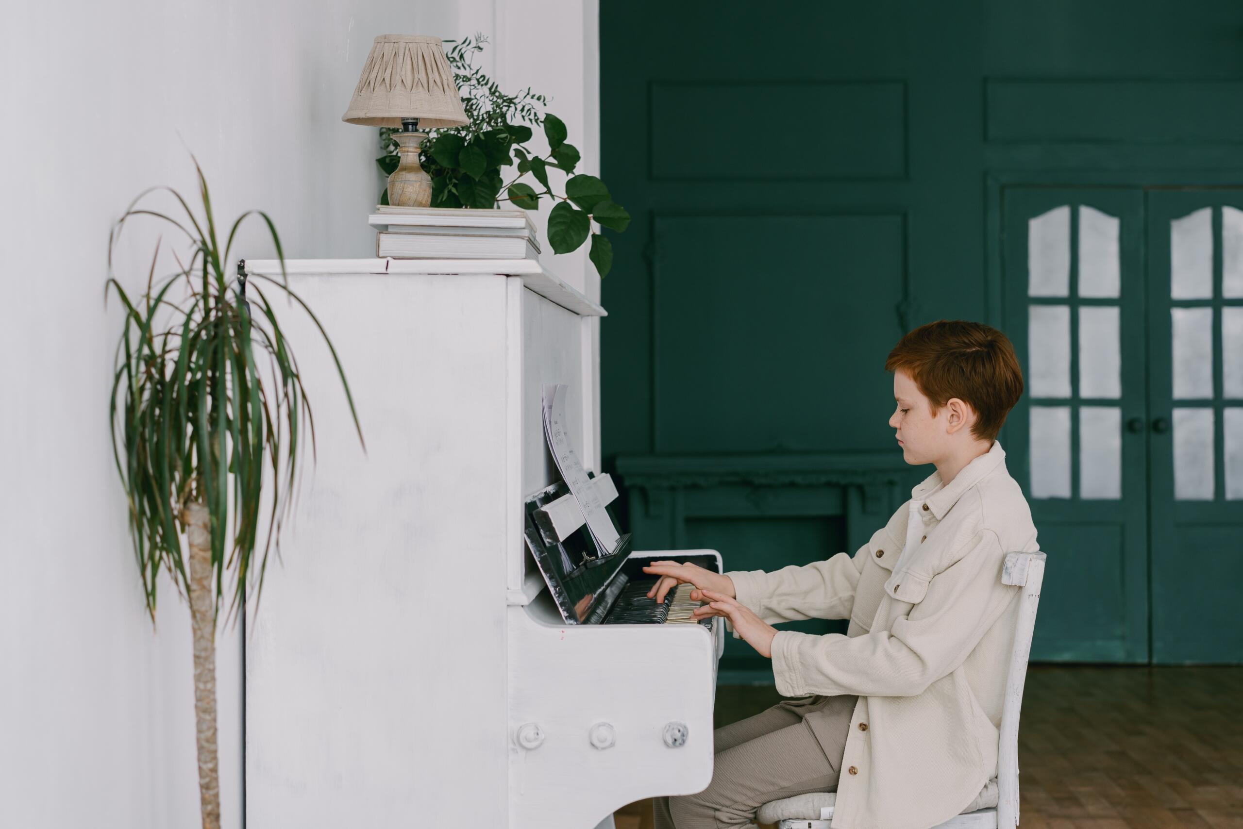 boy playing a white piano