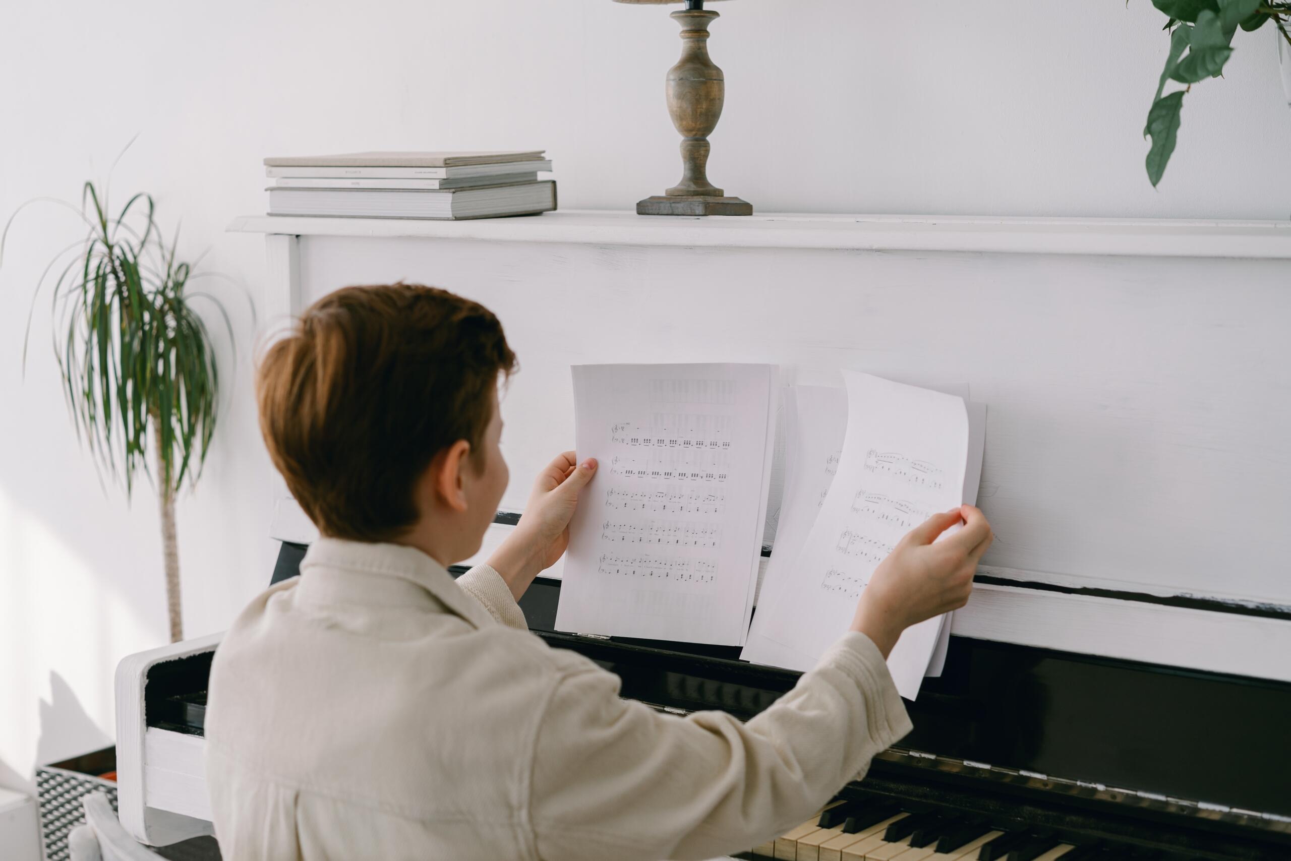 boy playing a white piano and reading sheet music