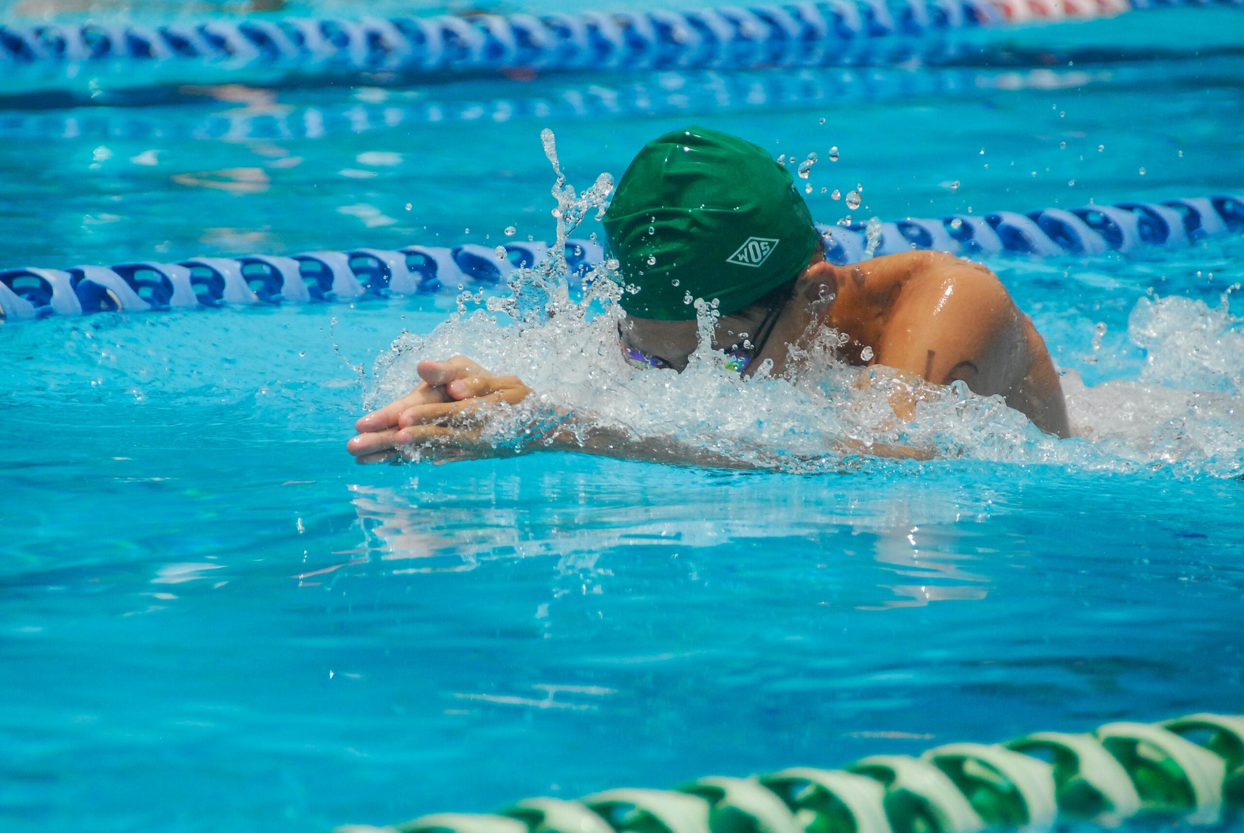 person in swimming pool with lanes wearing swimming cap and goggles