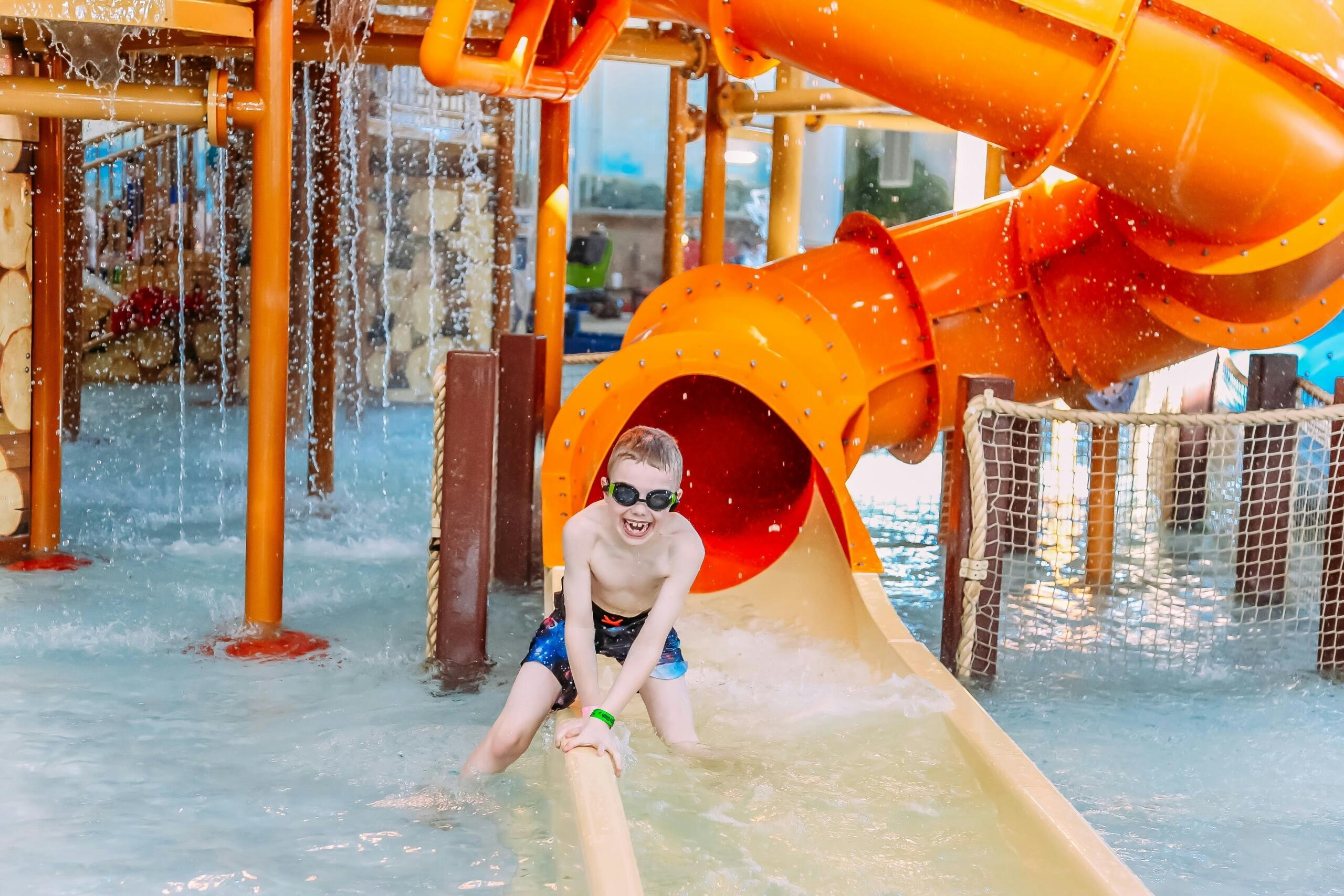 A child emerges from a water slide.