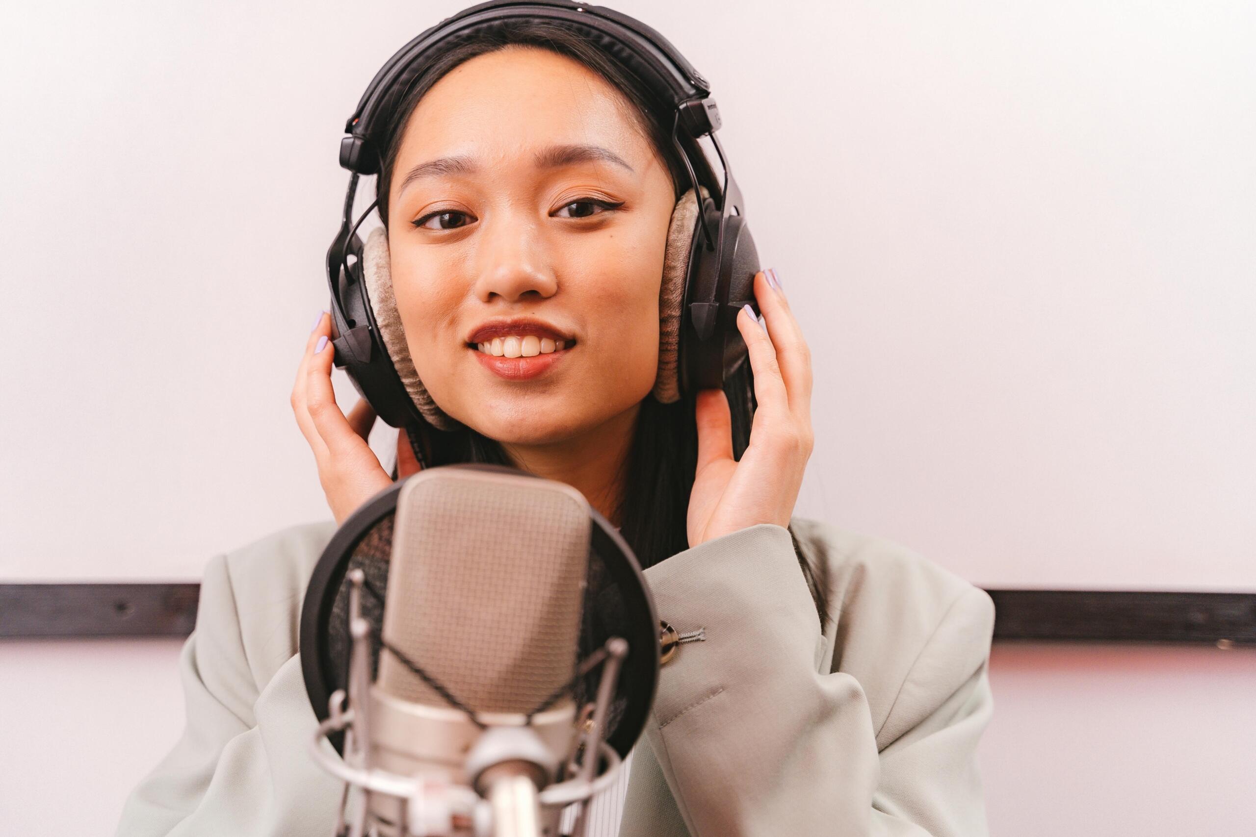 woman behind a microphone in recording studio wearing headphones