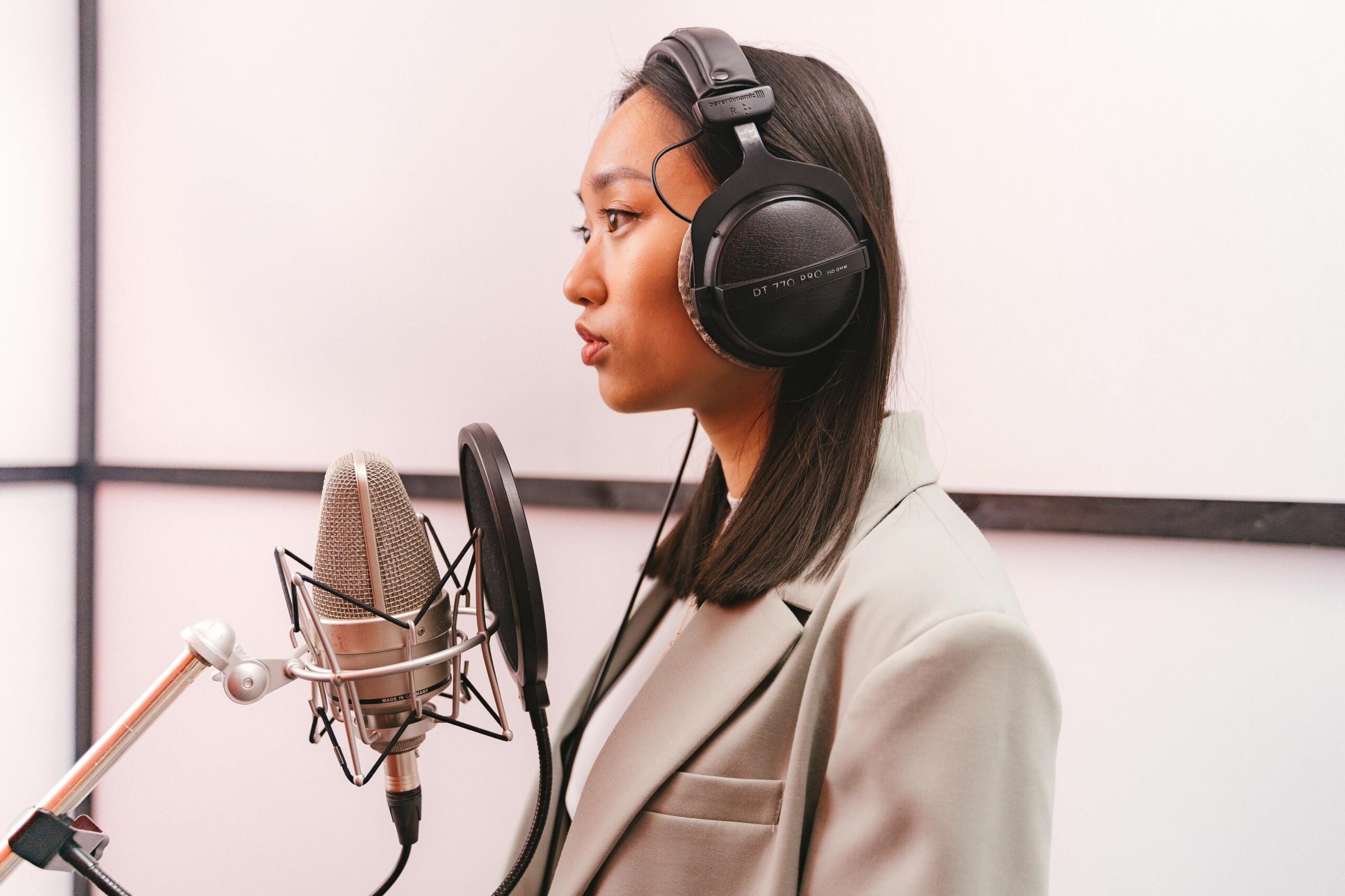 profile of woman behind a microphone in recording studio wearing headphones