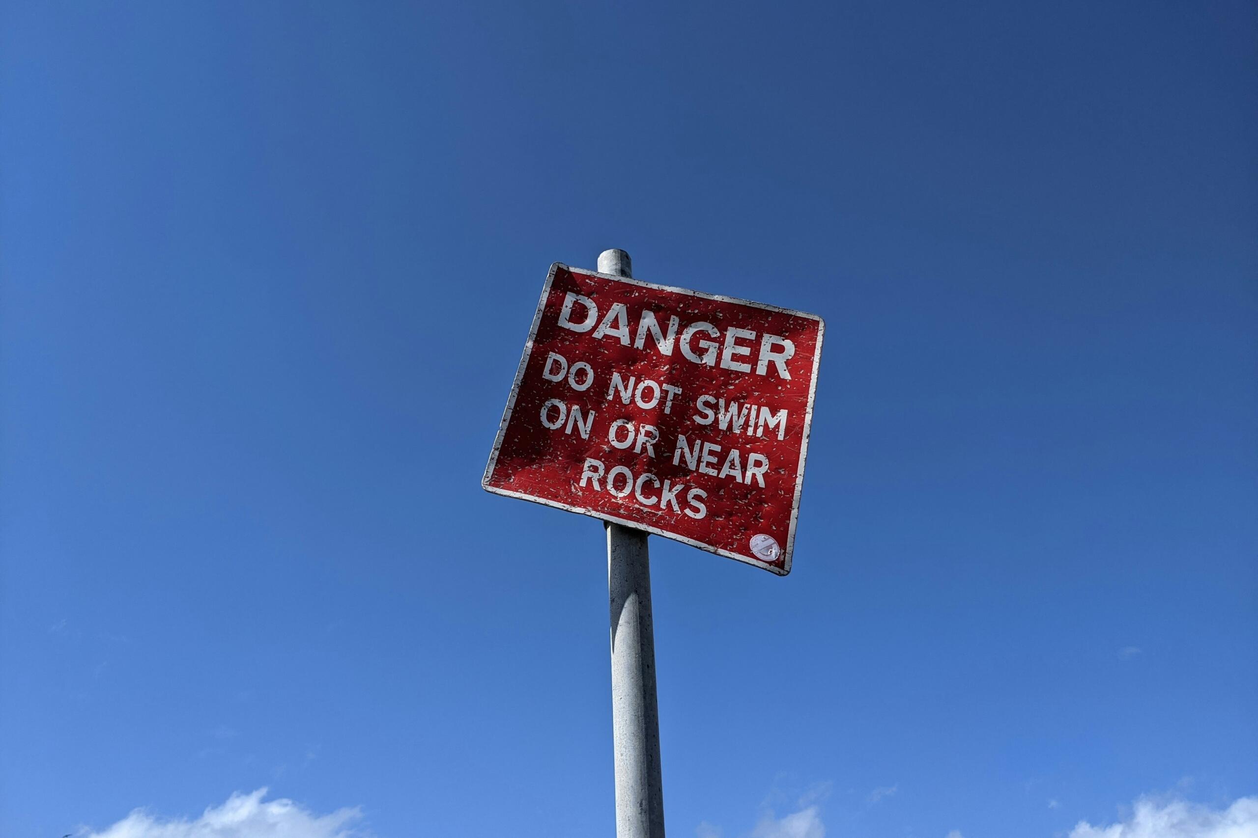 Danger sign that says do not swim on or near rocks