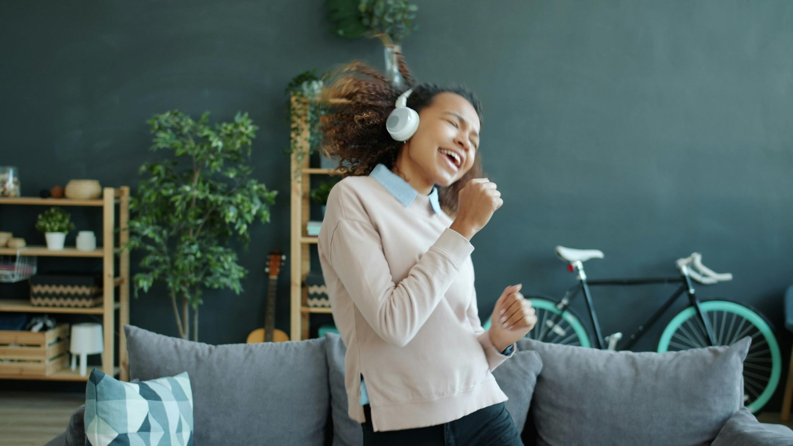 girl wearing headphones and singing into an imaginary microphone in her living room