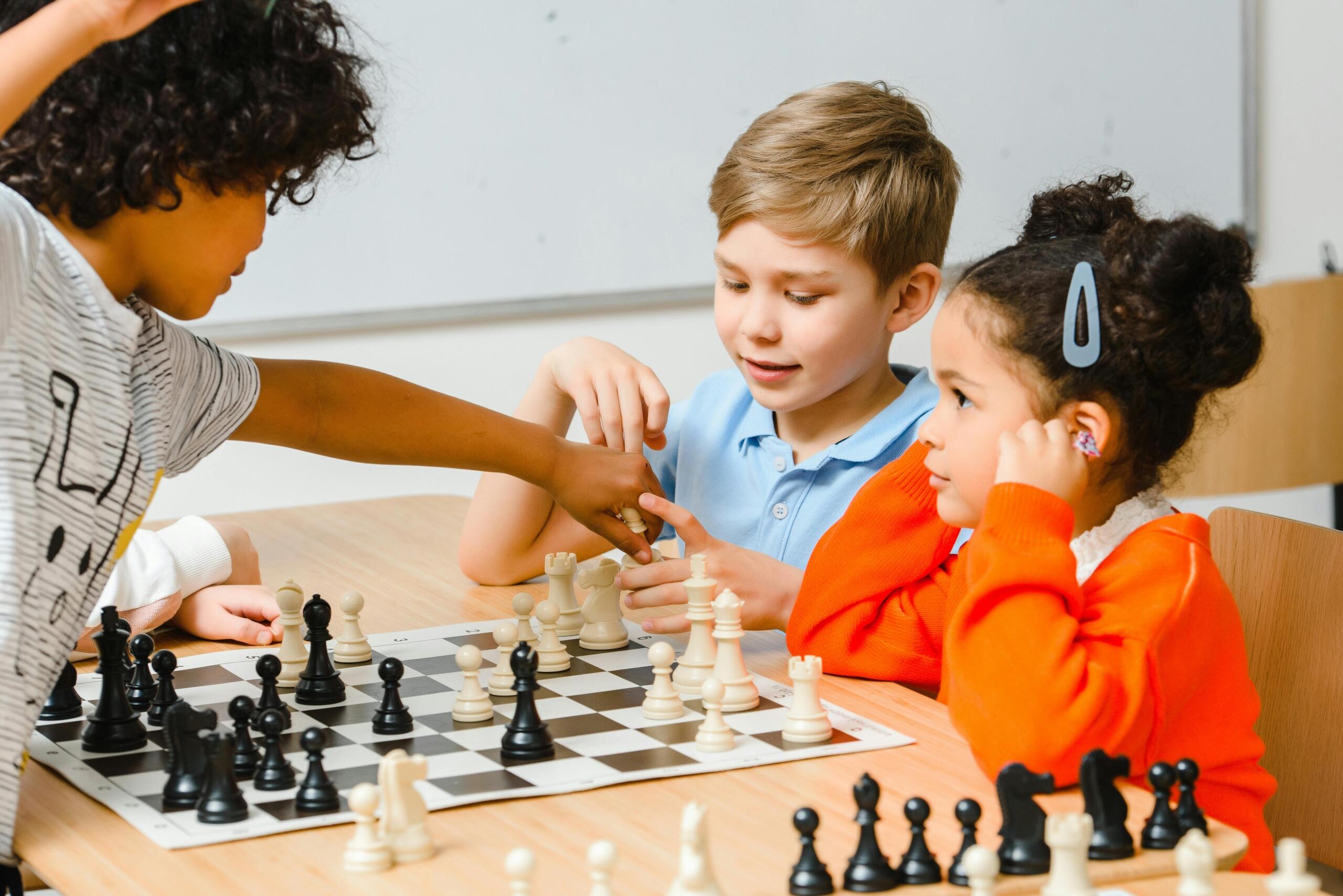 four preschoolers sitting around a table playing chess
