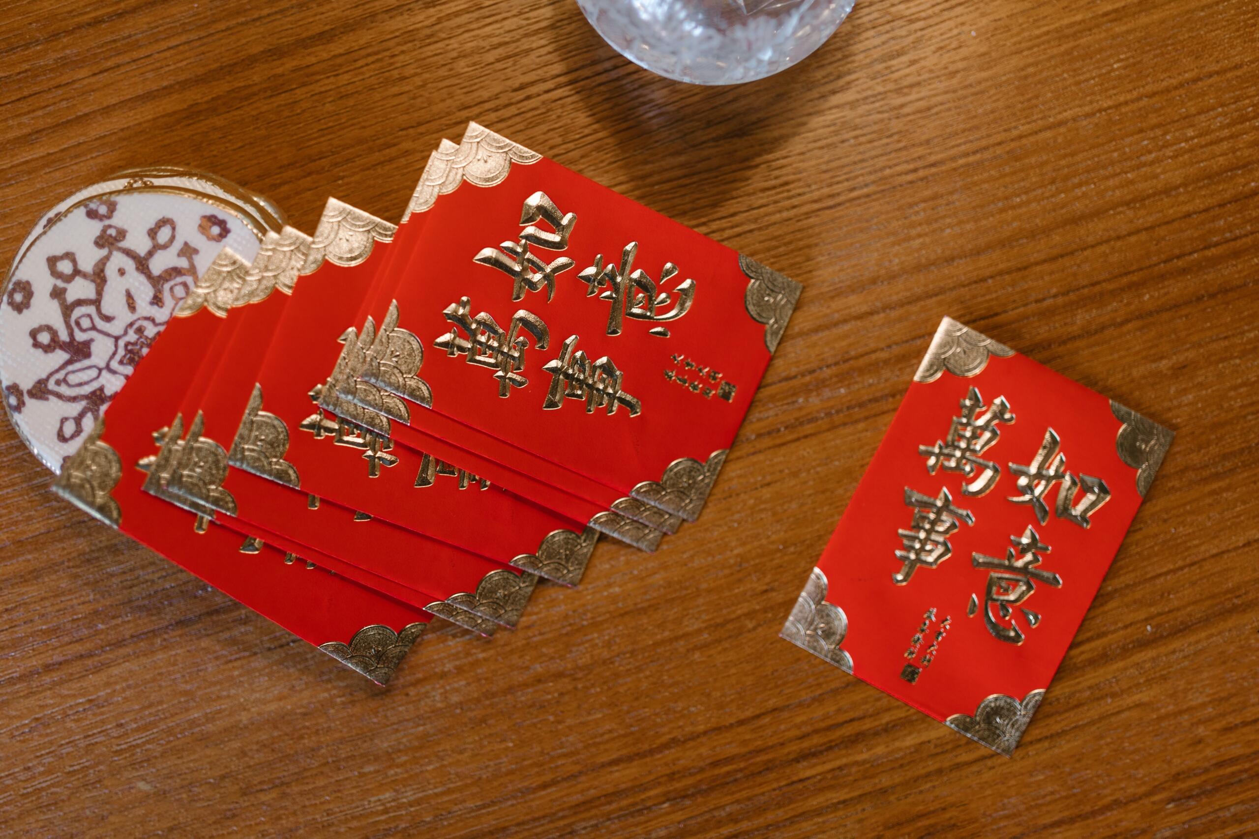 assortment of red cards embossed with gold chines characters placed on a wooden table