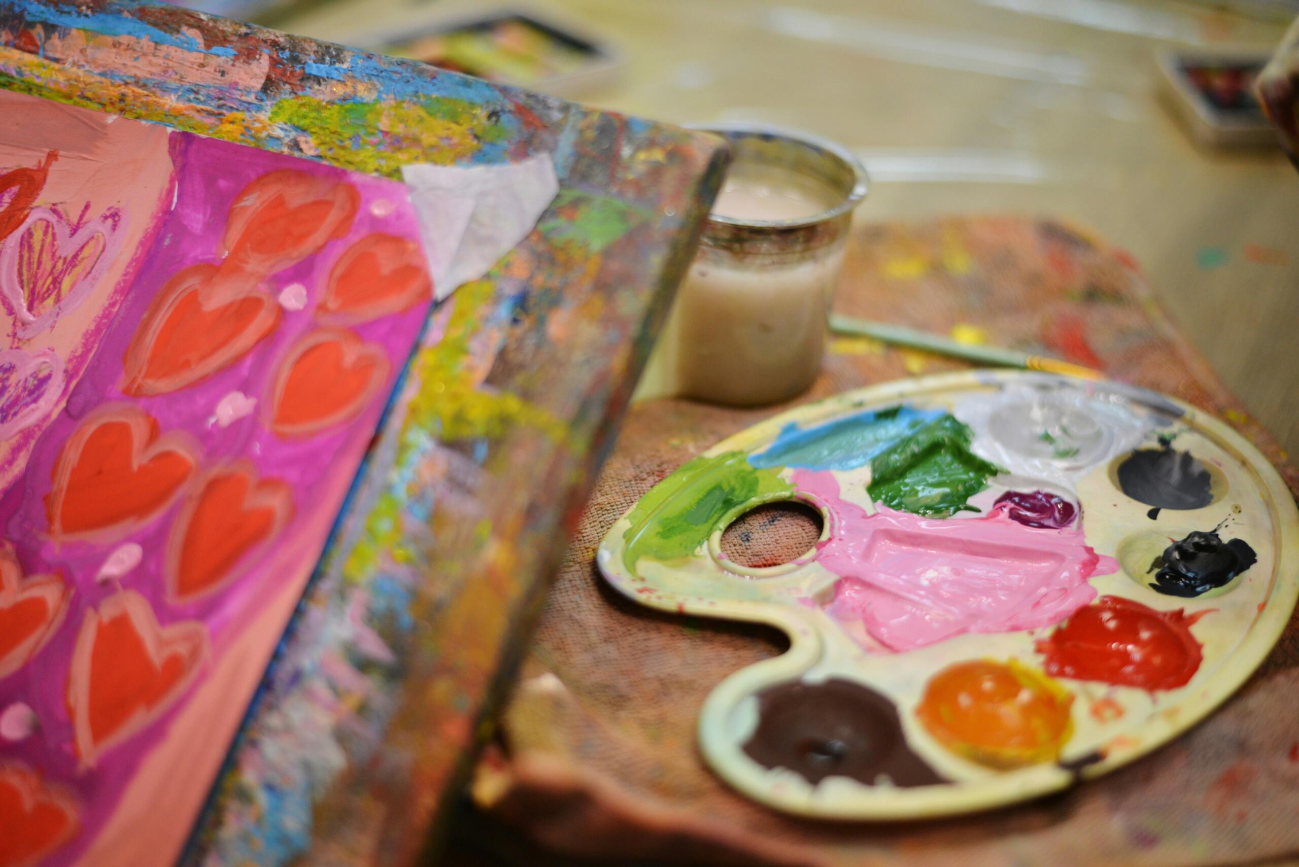 a paint palette on a tray with a framed painting in the foreground