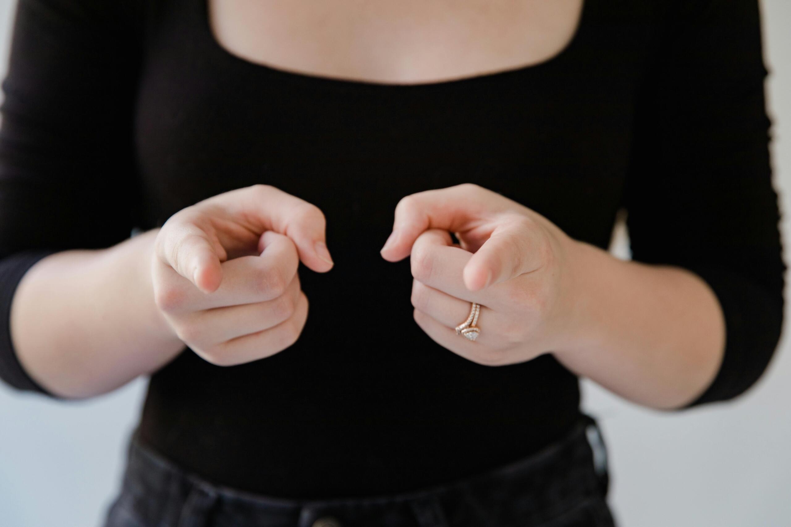 woman making sign language gesture pointing both index fingers forward