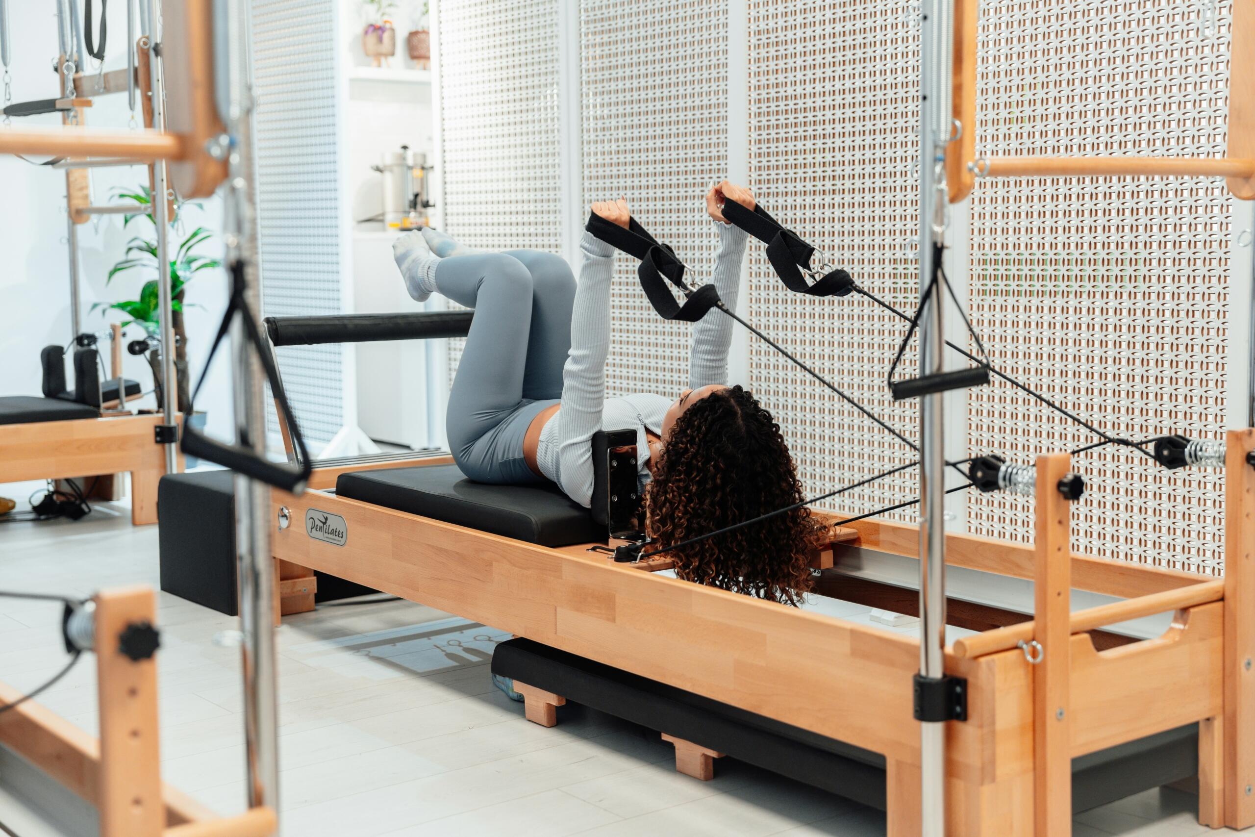 woman using a Reformer pilates machine in a pilates studio