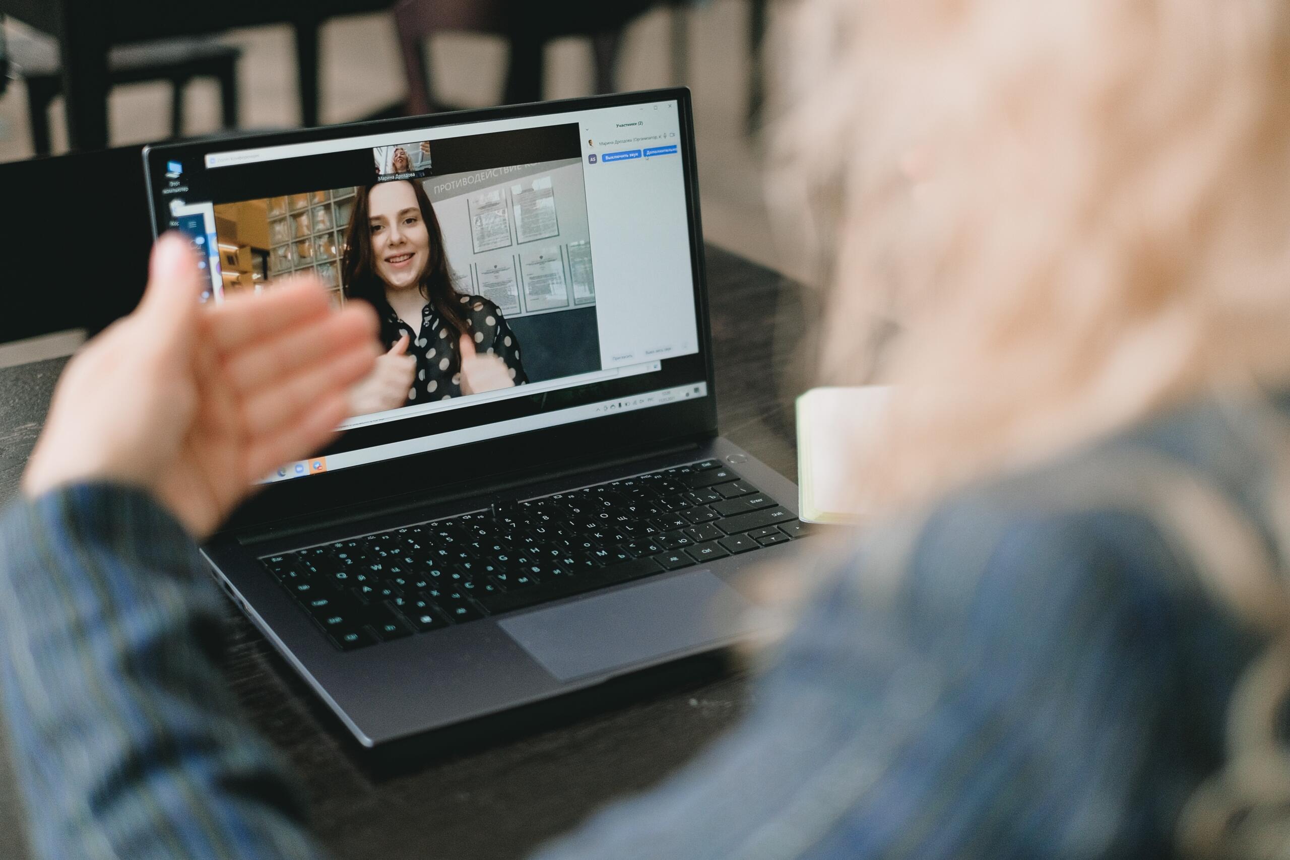 two women connected in online meeting on laptop using sign language